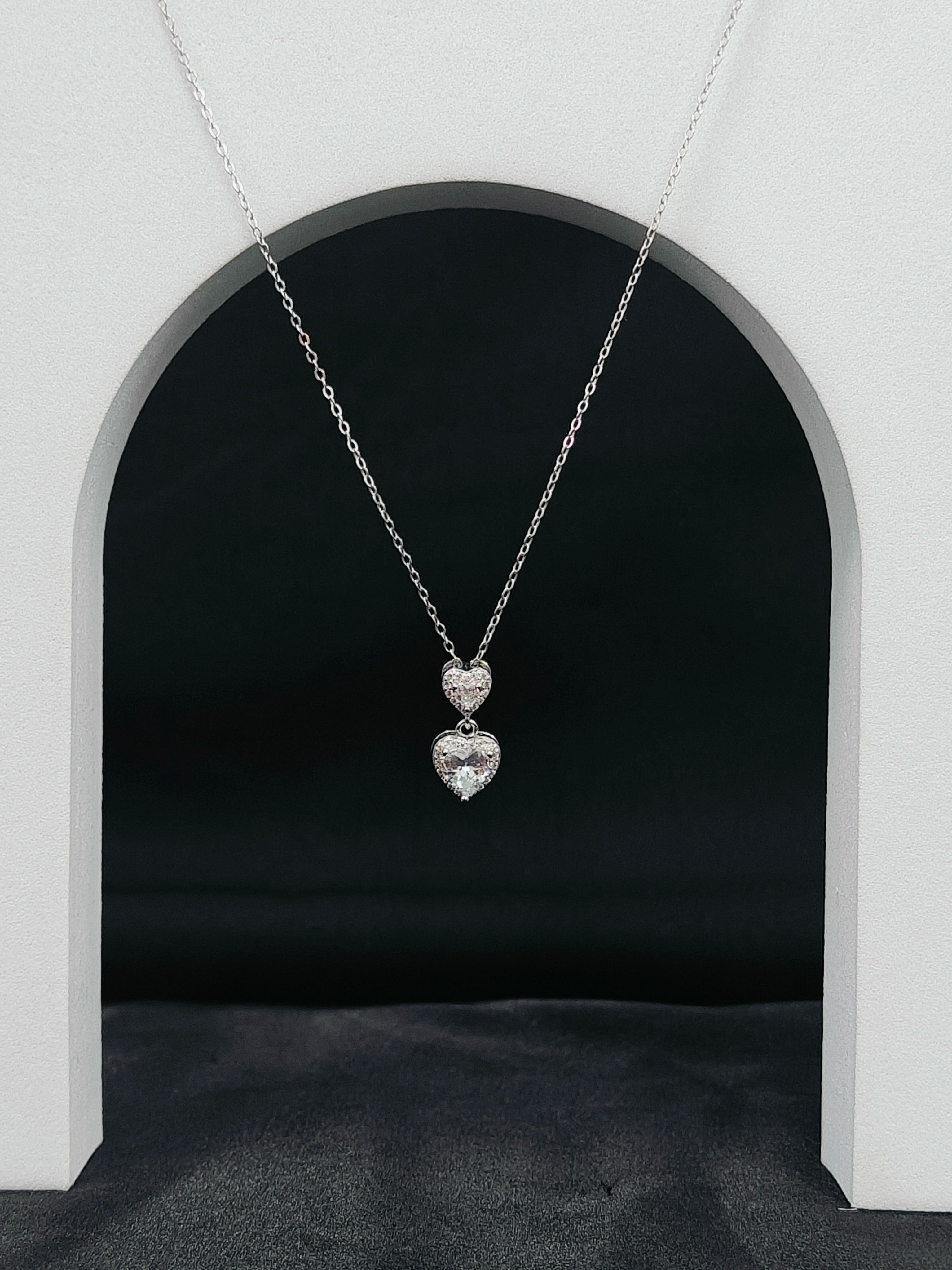 Silver necklace with heart-shaped pendant on a dark background