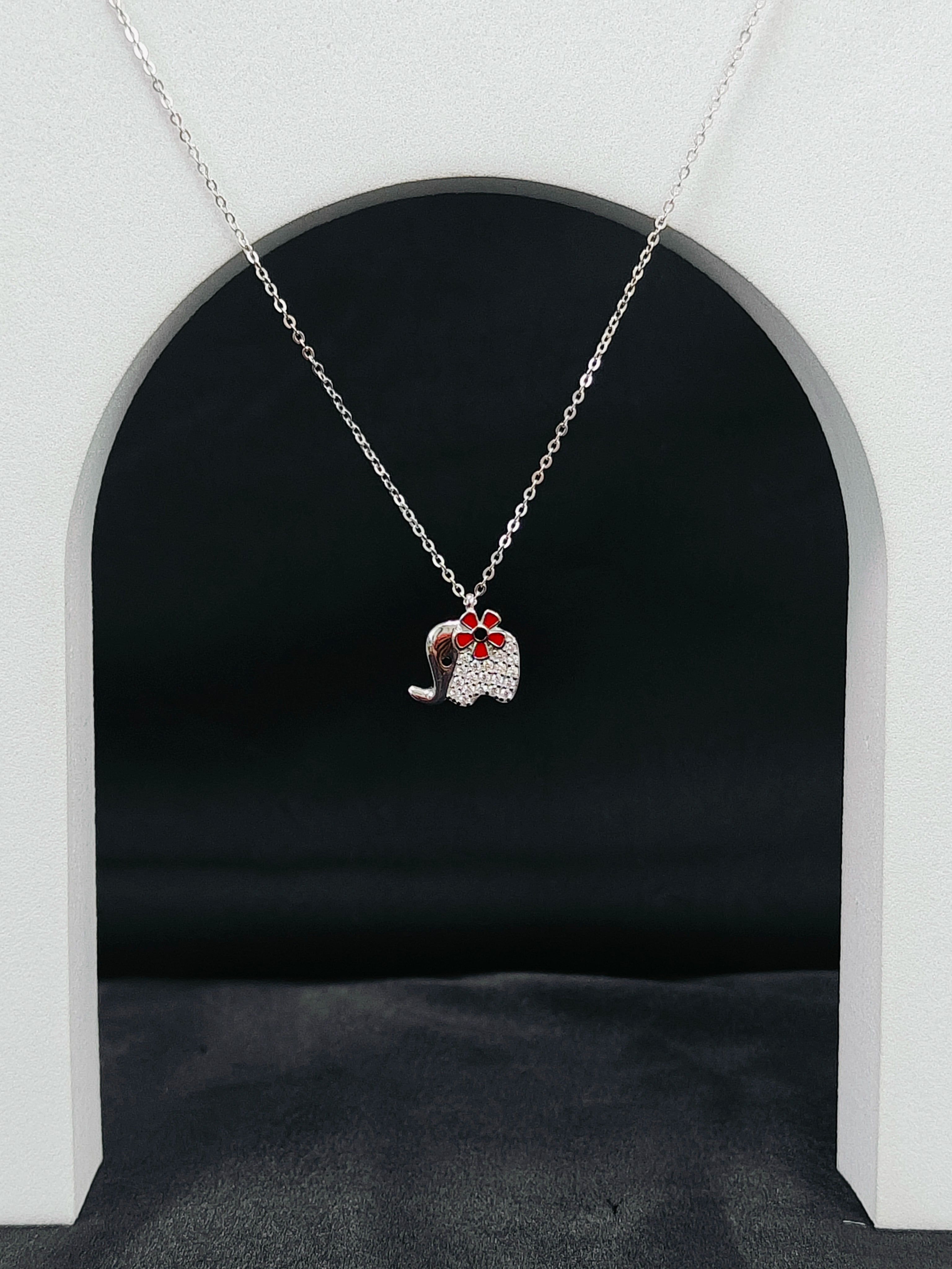 Necklace with a pendant shaped like a cat in a red bow tie against a black background