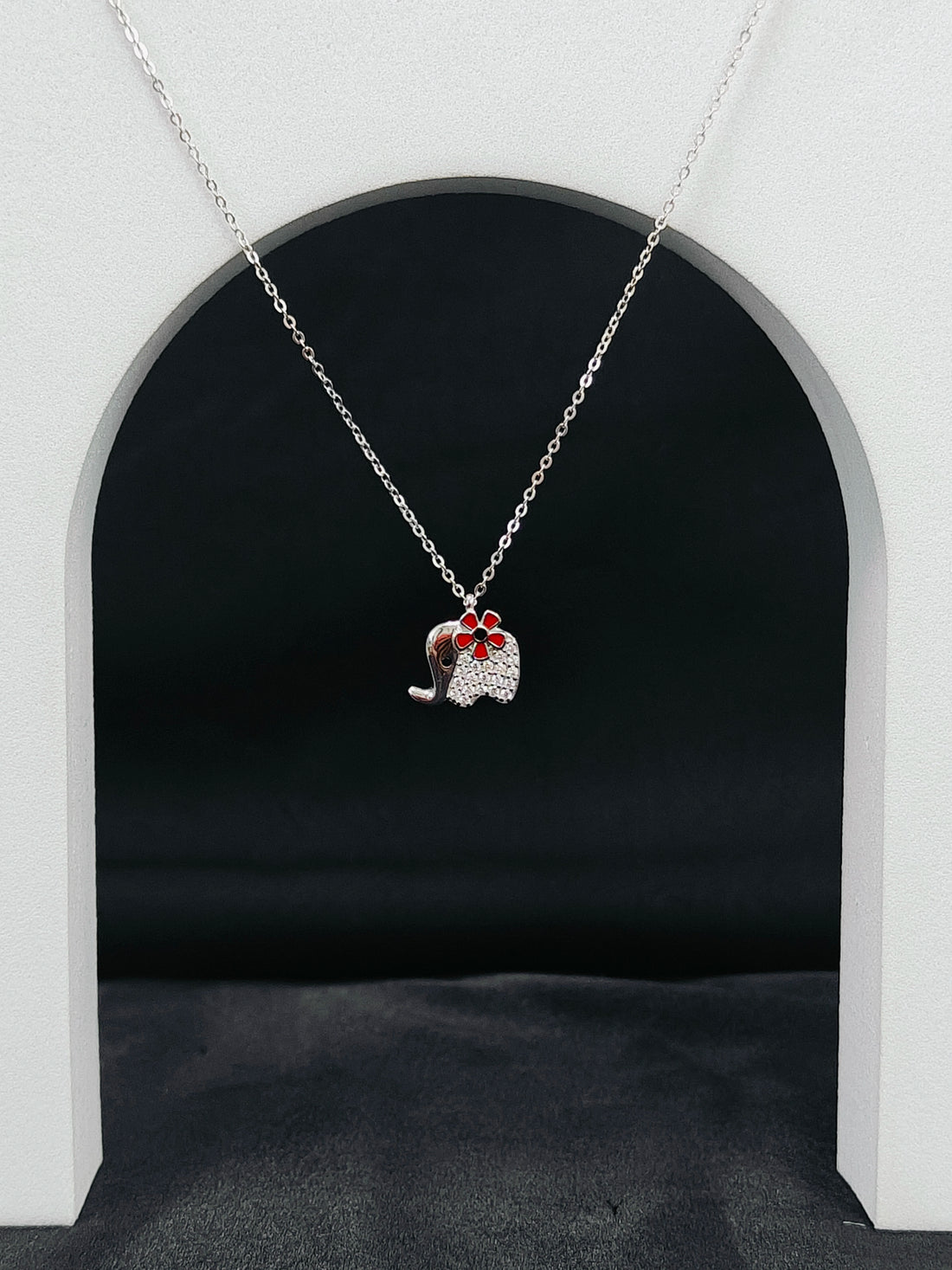 Necklace with a pendant shaped like a cat in a red bow tie against a black background