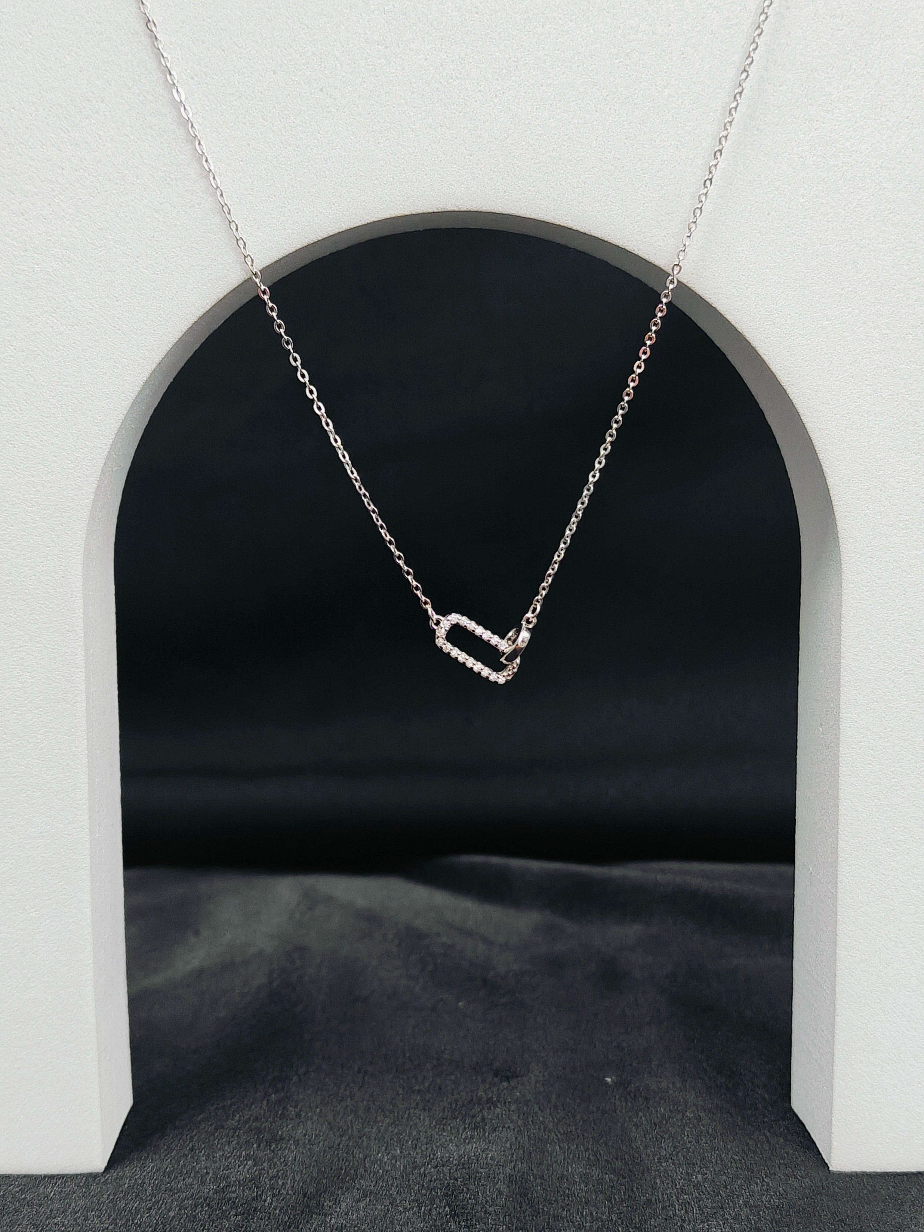 Silver necklace with a heart-shaped pendant on a white archway background