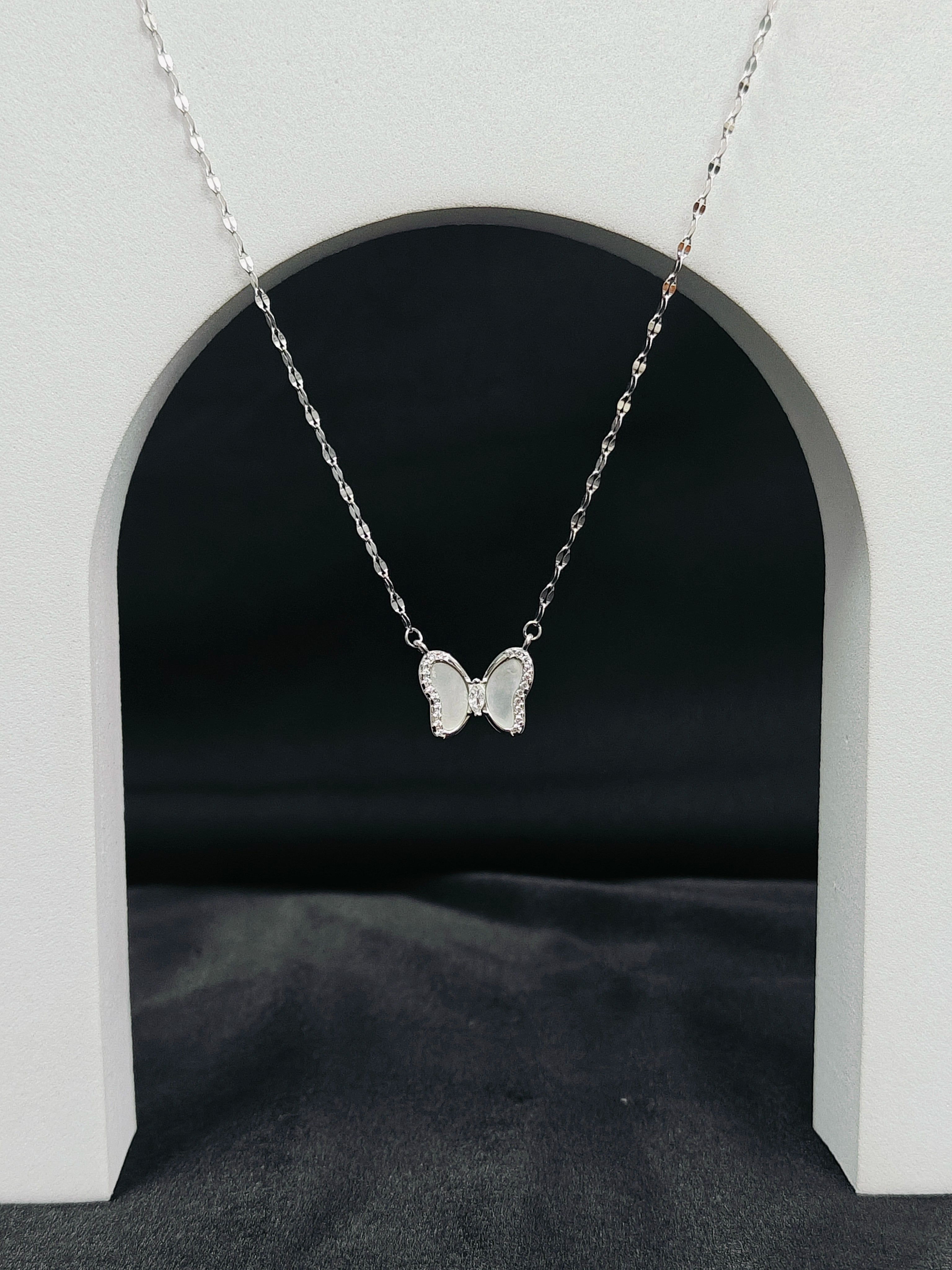 Silver butterfly necklace on a dark background