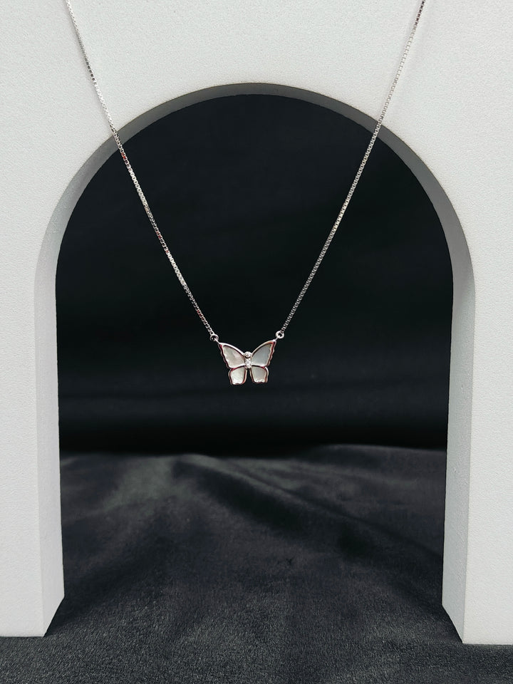 Butterfly necklace on a dark background with a white archway