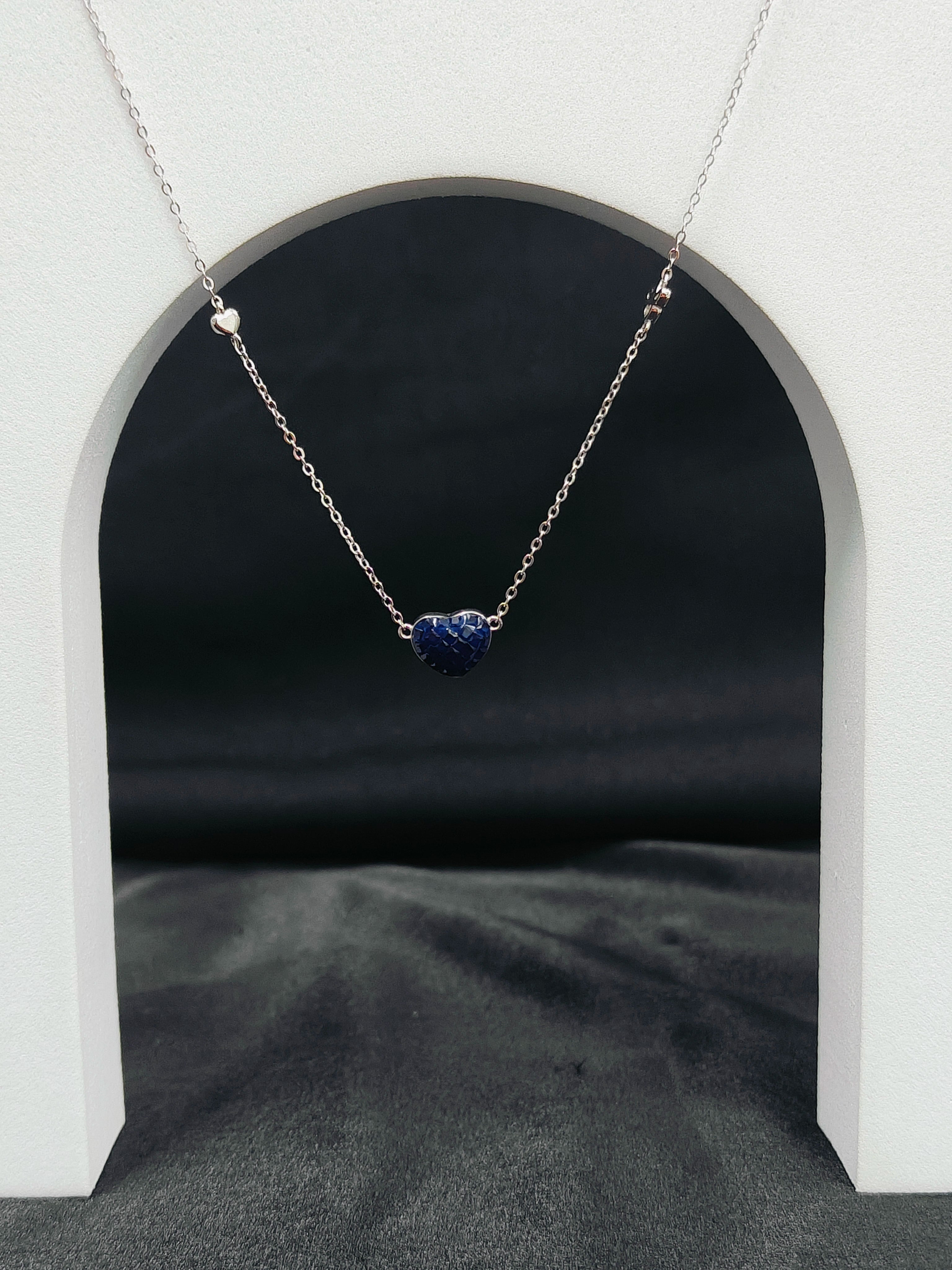 Necklace with a blue heart pendant on a dark background