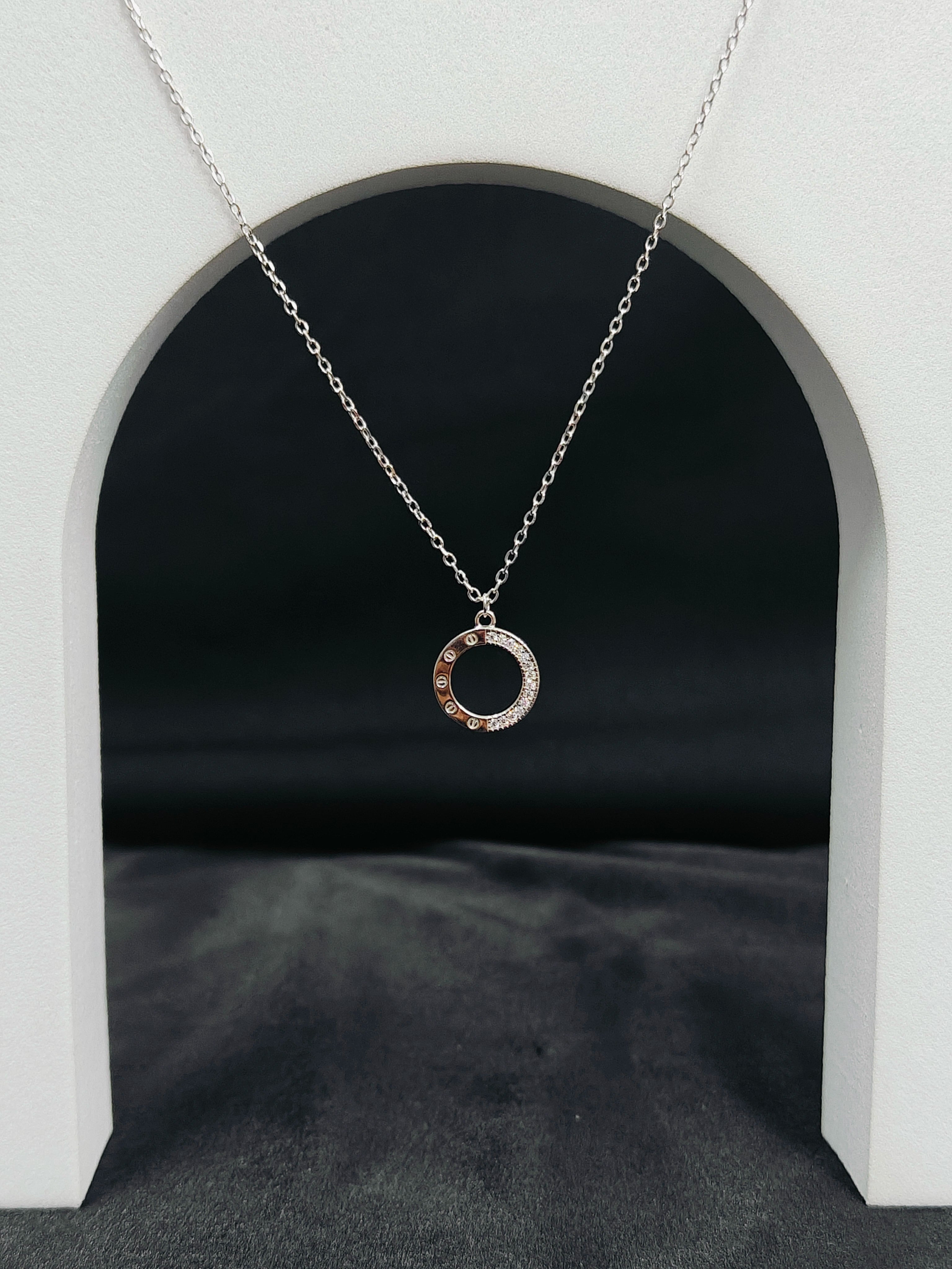 Silver necklace with a circular pendant on a black background