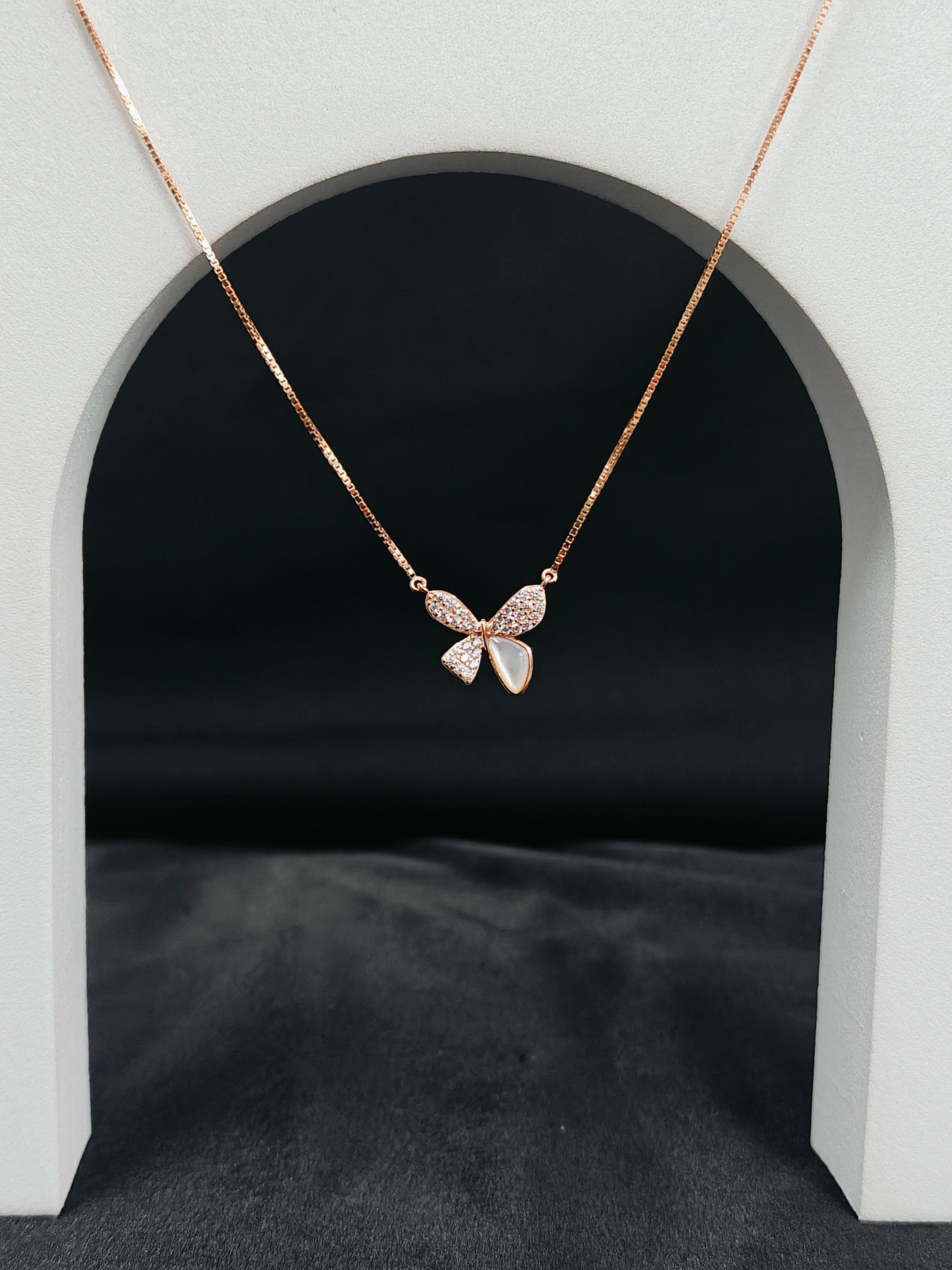 Butterfly necklace on a black background with a white arch