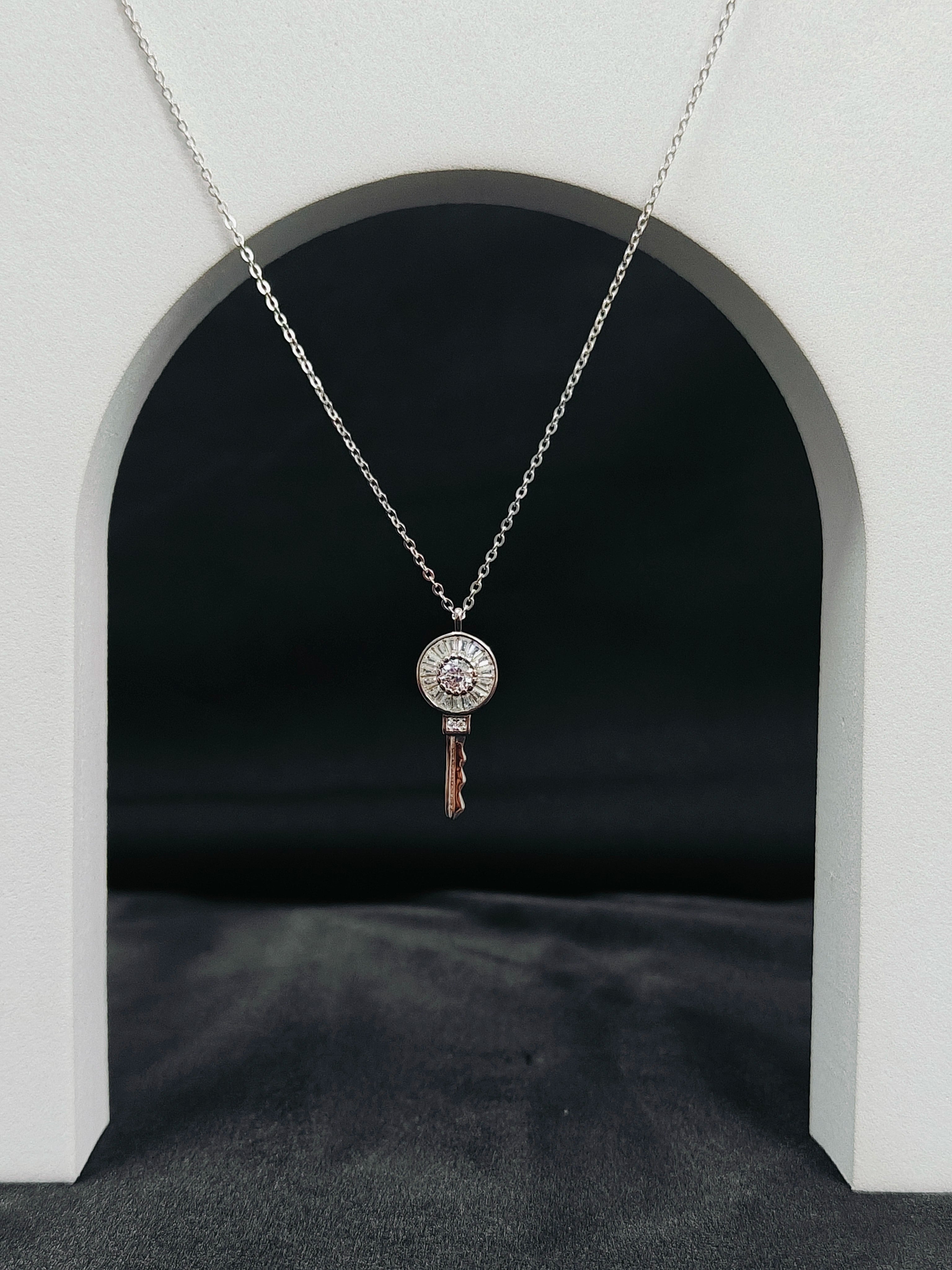 Silver necklace with a key-shaped pendant on a dark background