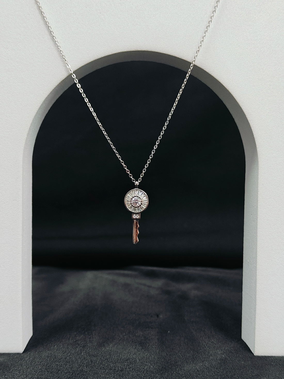Silver necklace with a key-shaped pendant on a dark background