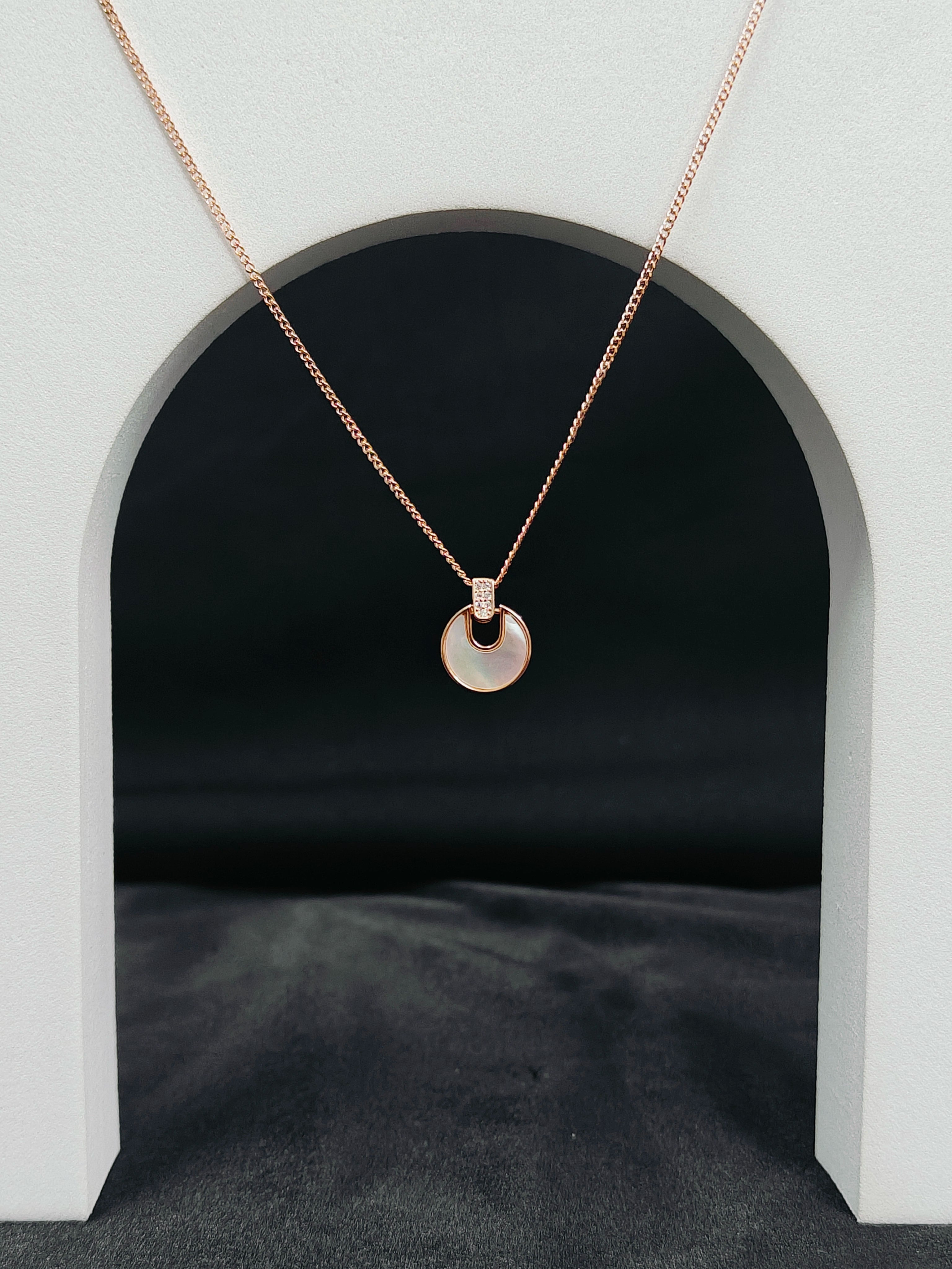 Rose gold necklace with a round pendant on a dark background