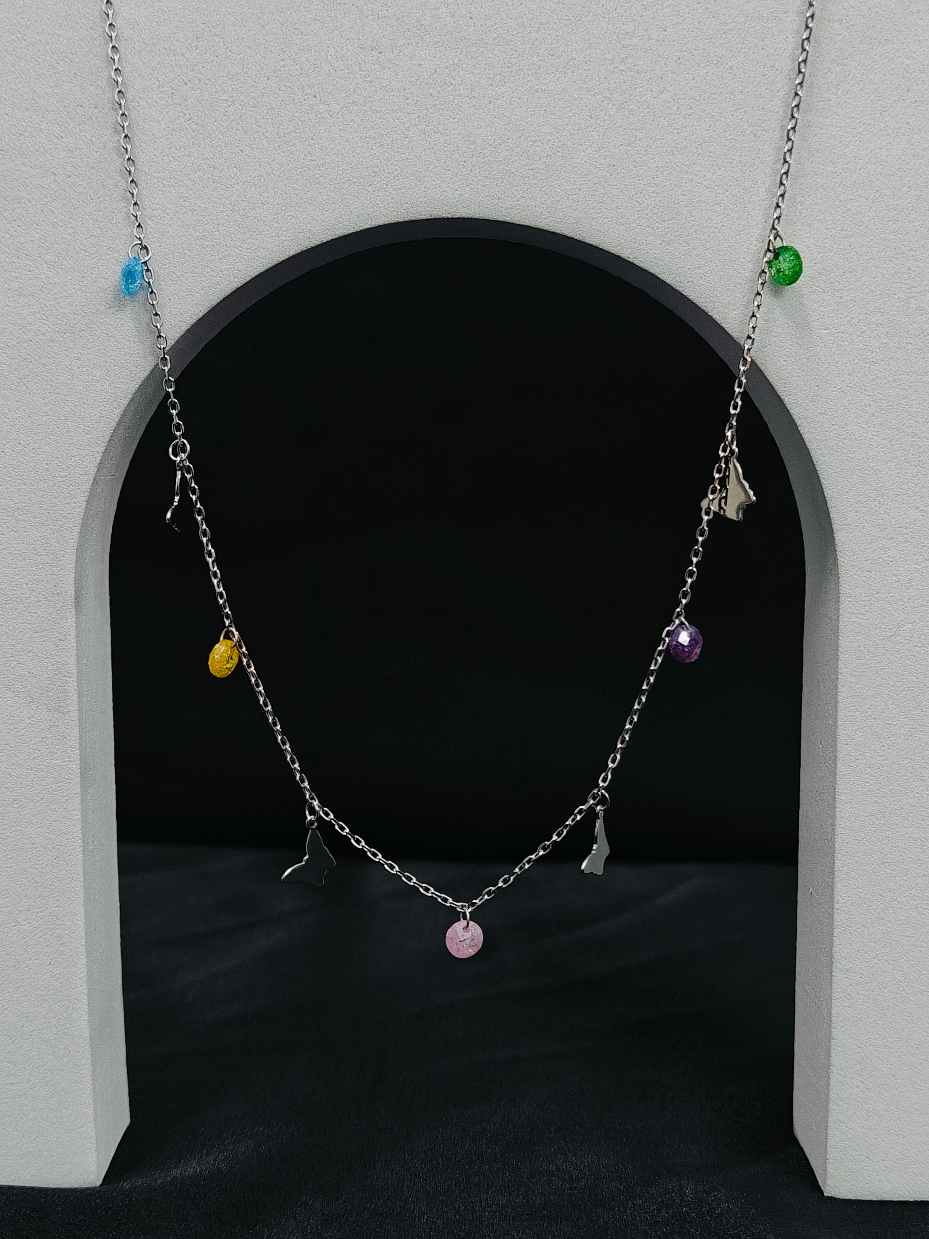 Necklace with colorful charms hanging in front of a dark archway