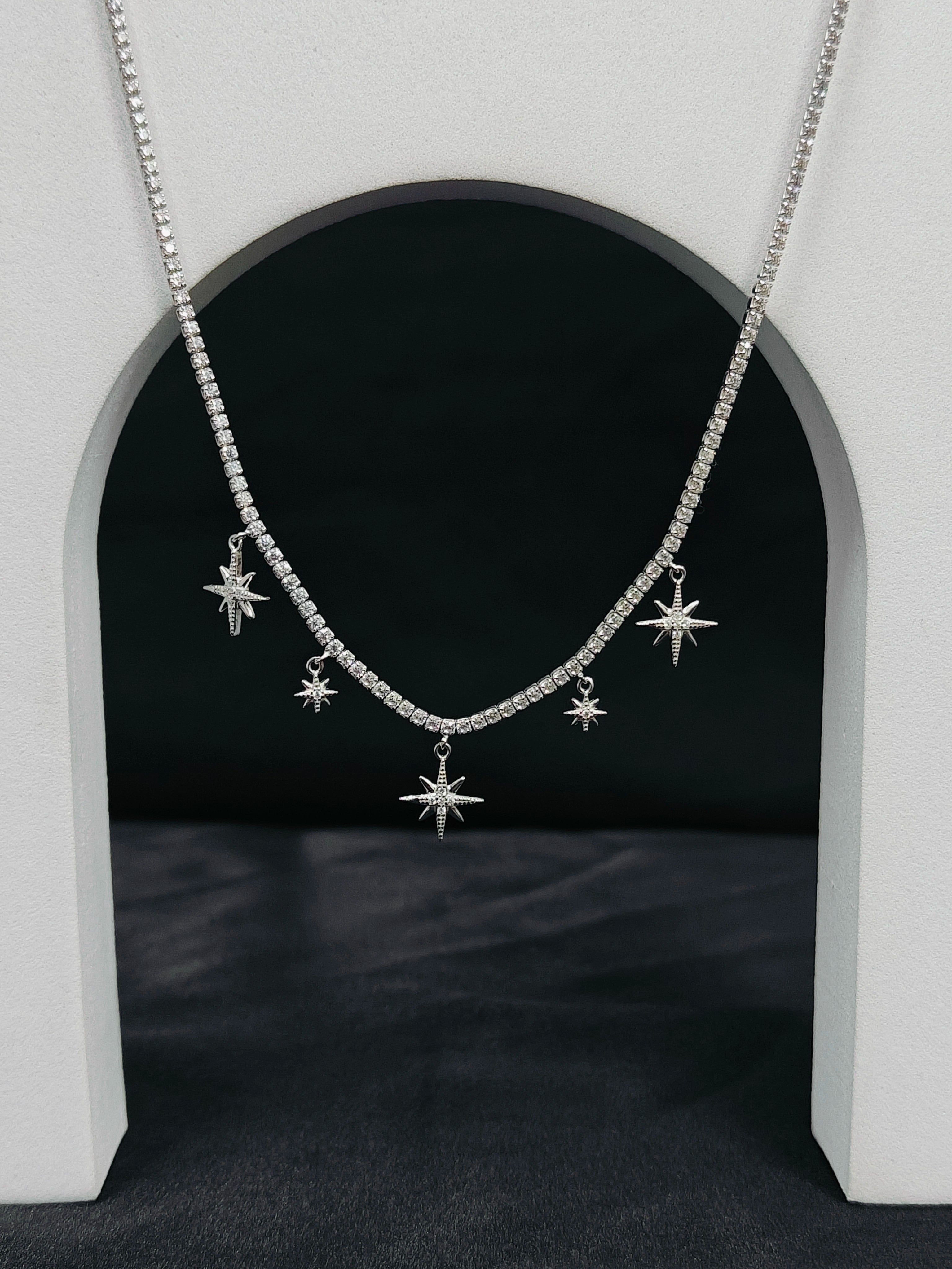 Silver necklace with star-shaped pendants on a dark background