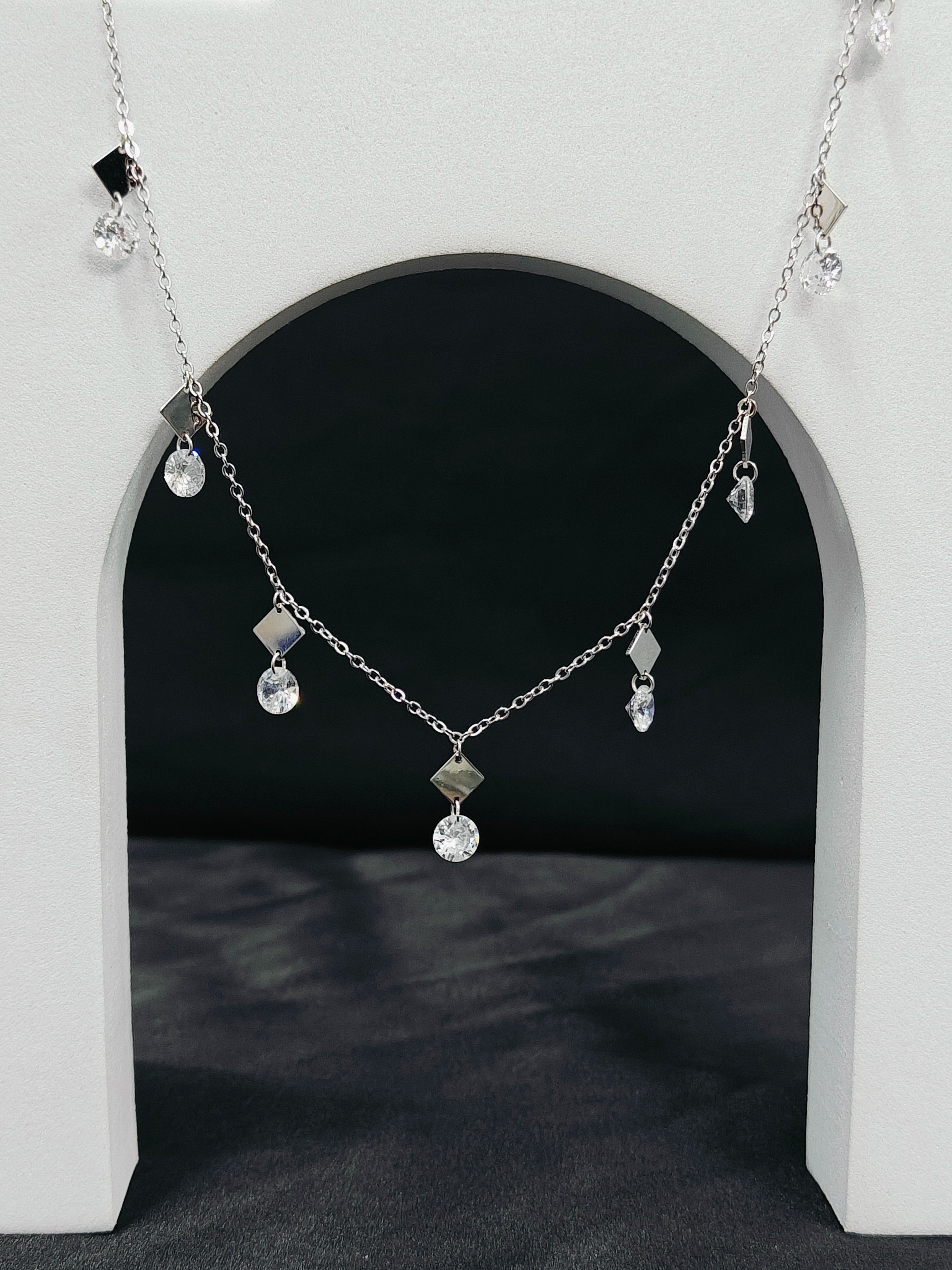 Silver necklace with pendant on a white arch background