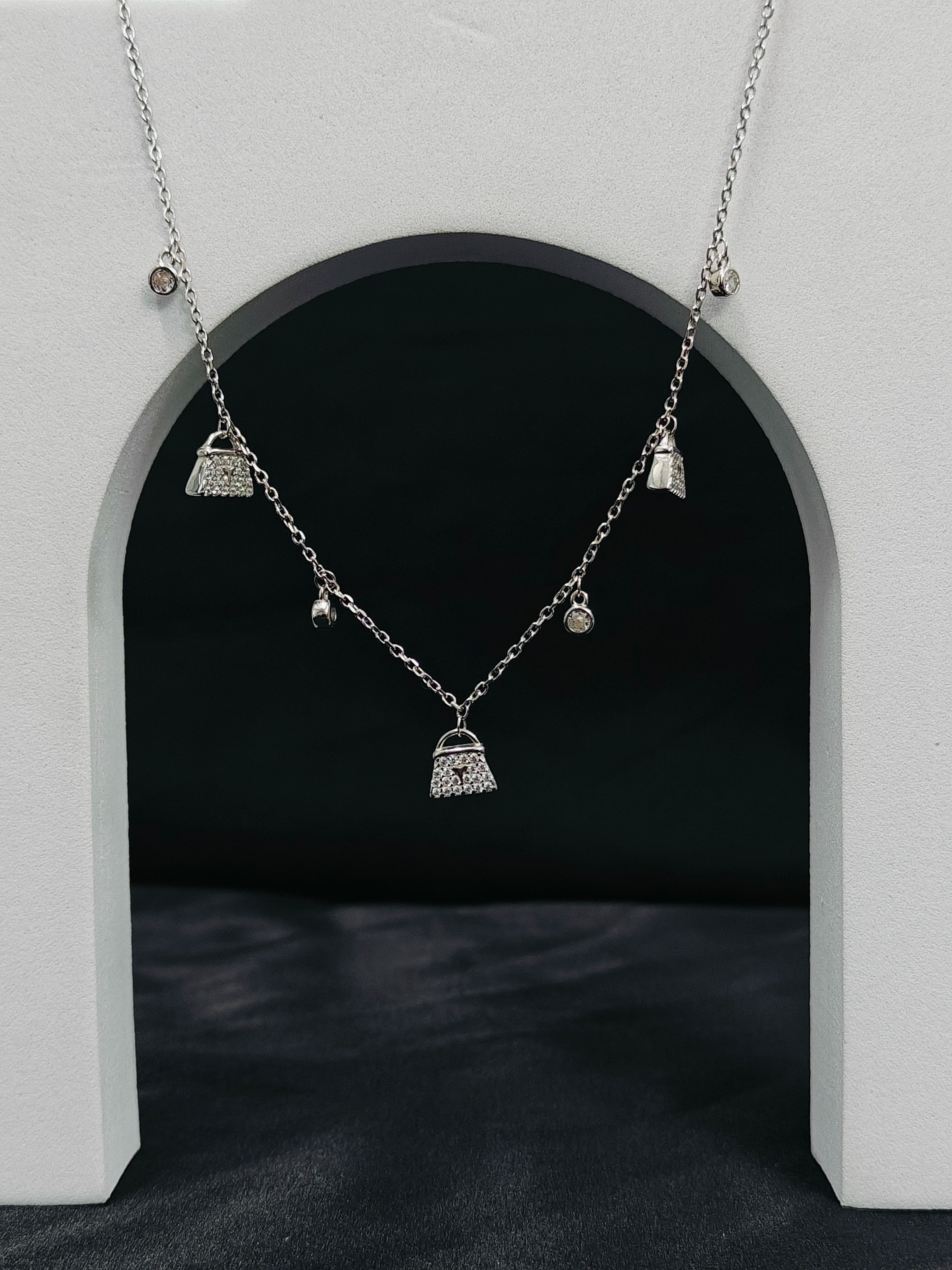 Necklace with small bag pendants hanging against a dark background