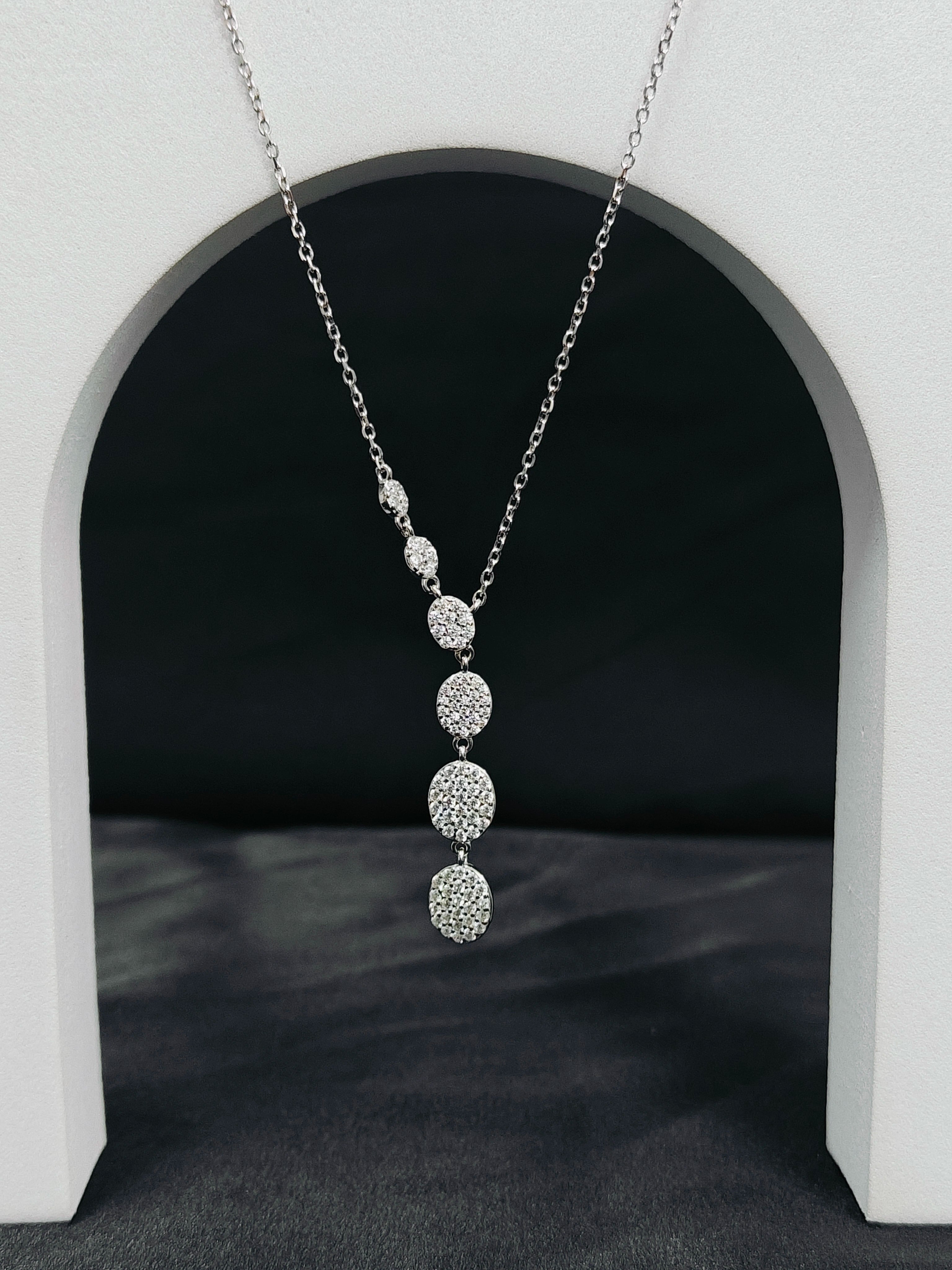 Silver necklace with circular pendants hanging against a black background