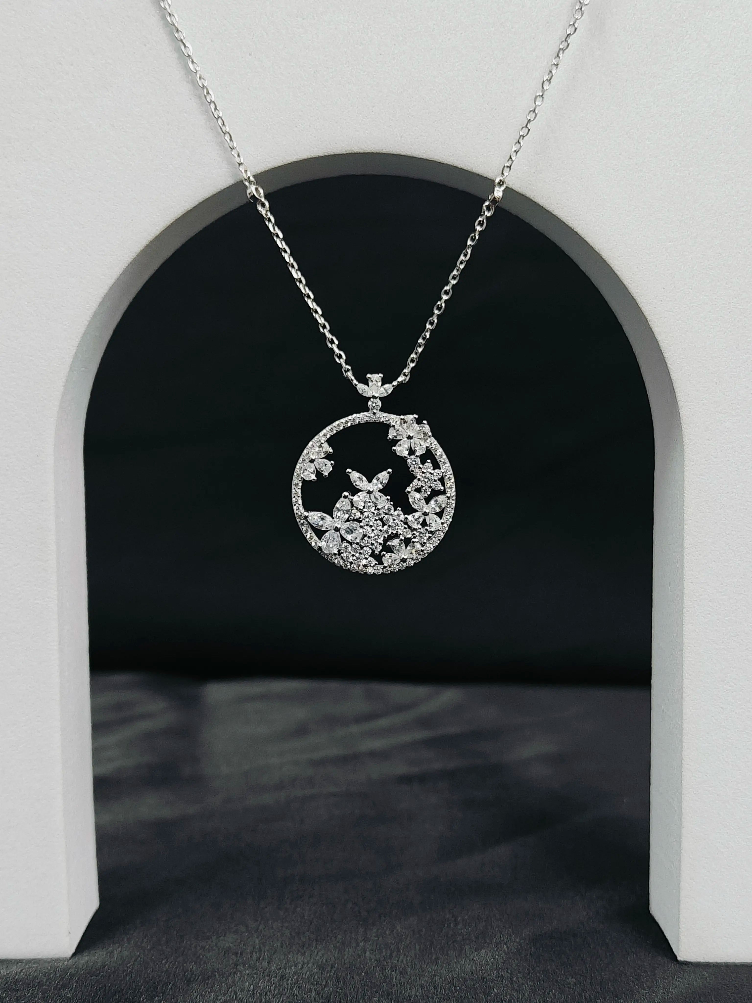 Silver necklace with a circular pendant featuring a butterfly design against a black background.