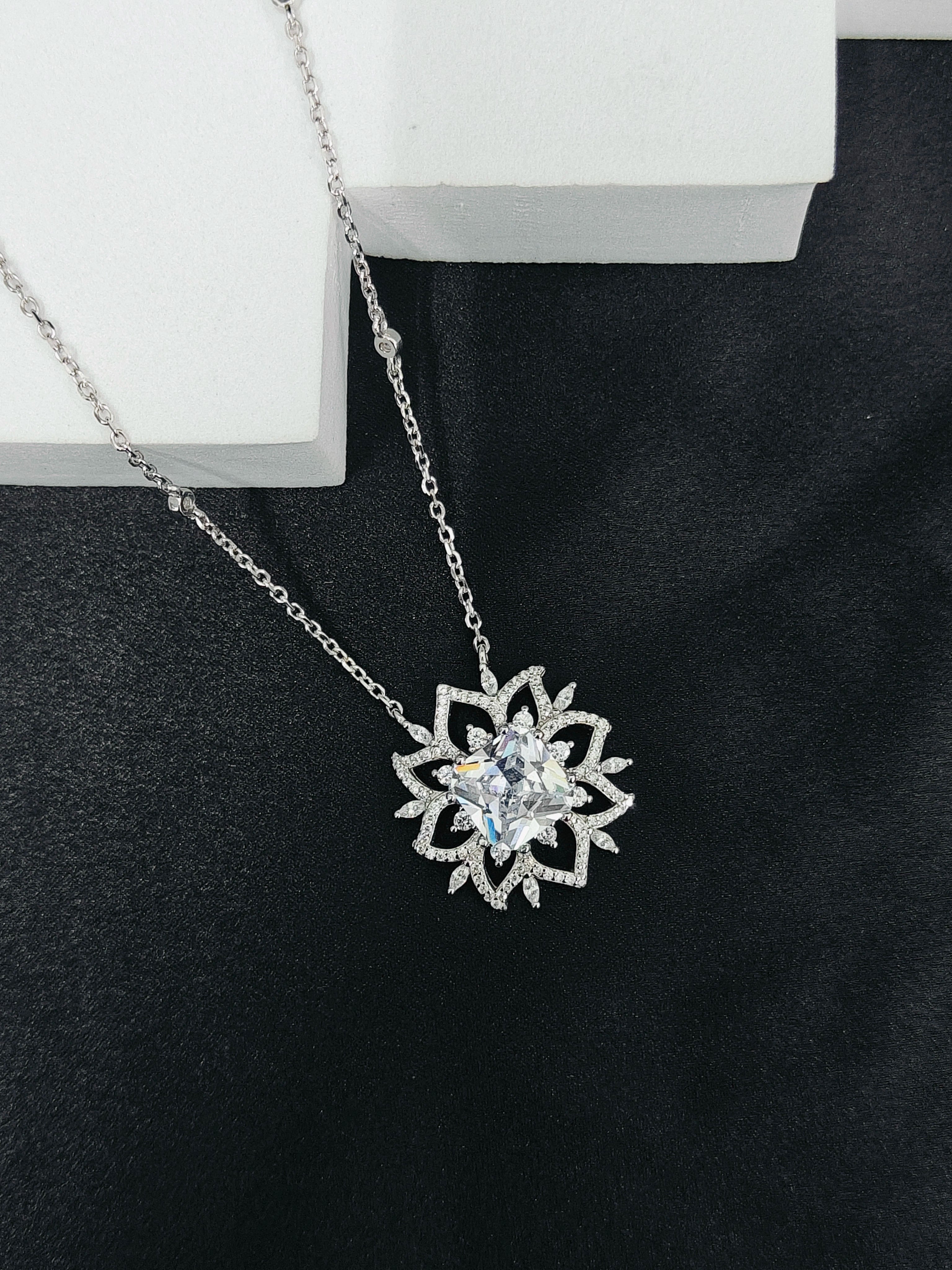 Silver necklace with a snowflake pendant on a black surface