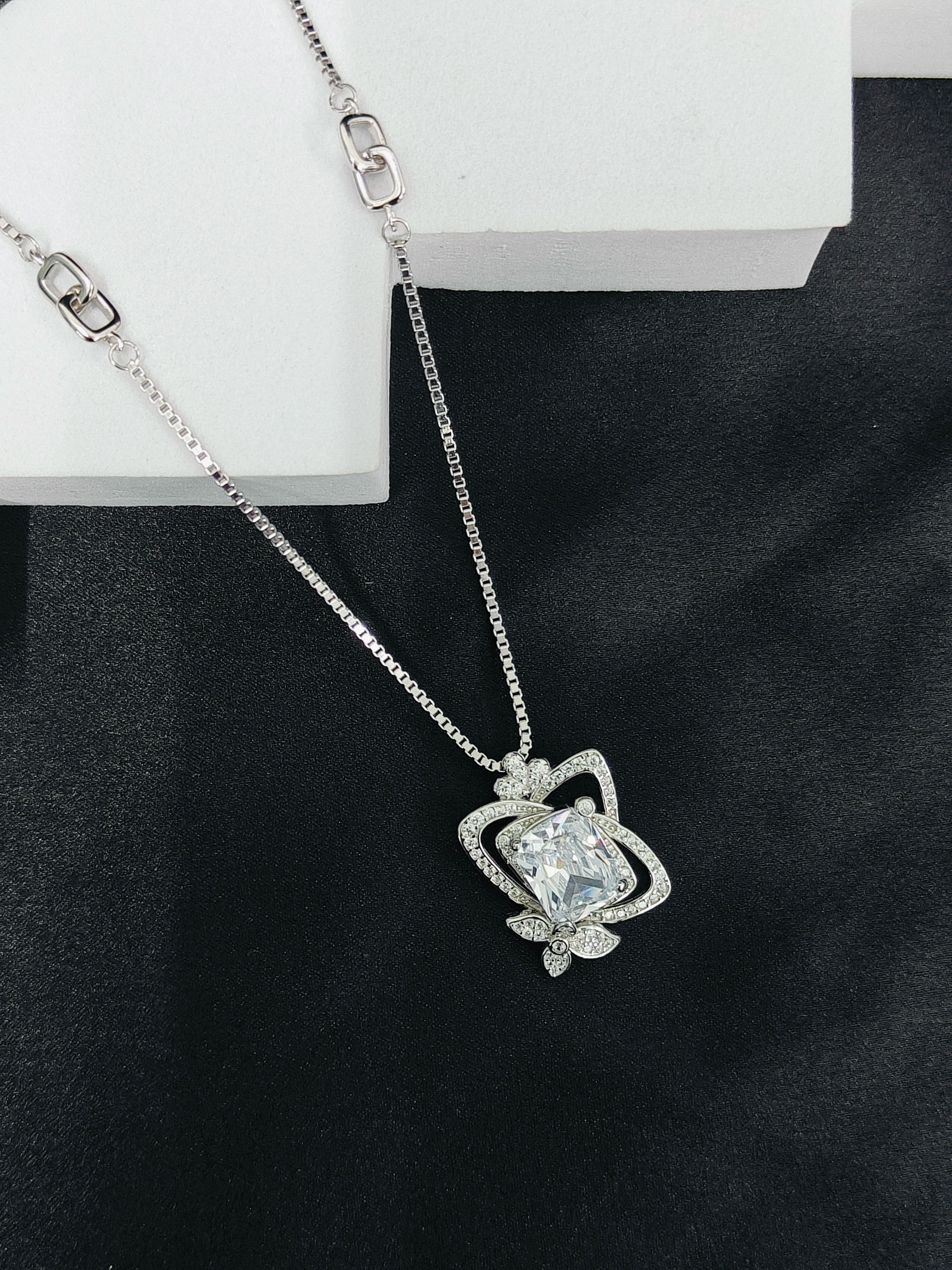 Silver necklace with a heart-shaped pendant on a black background