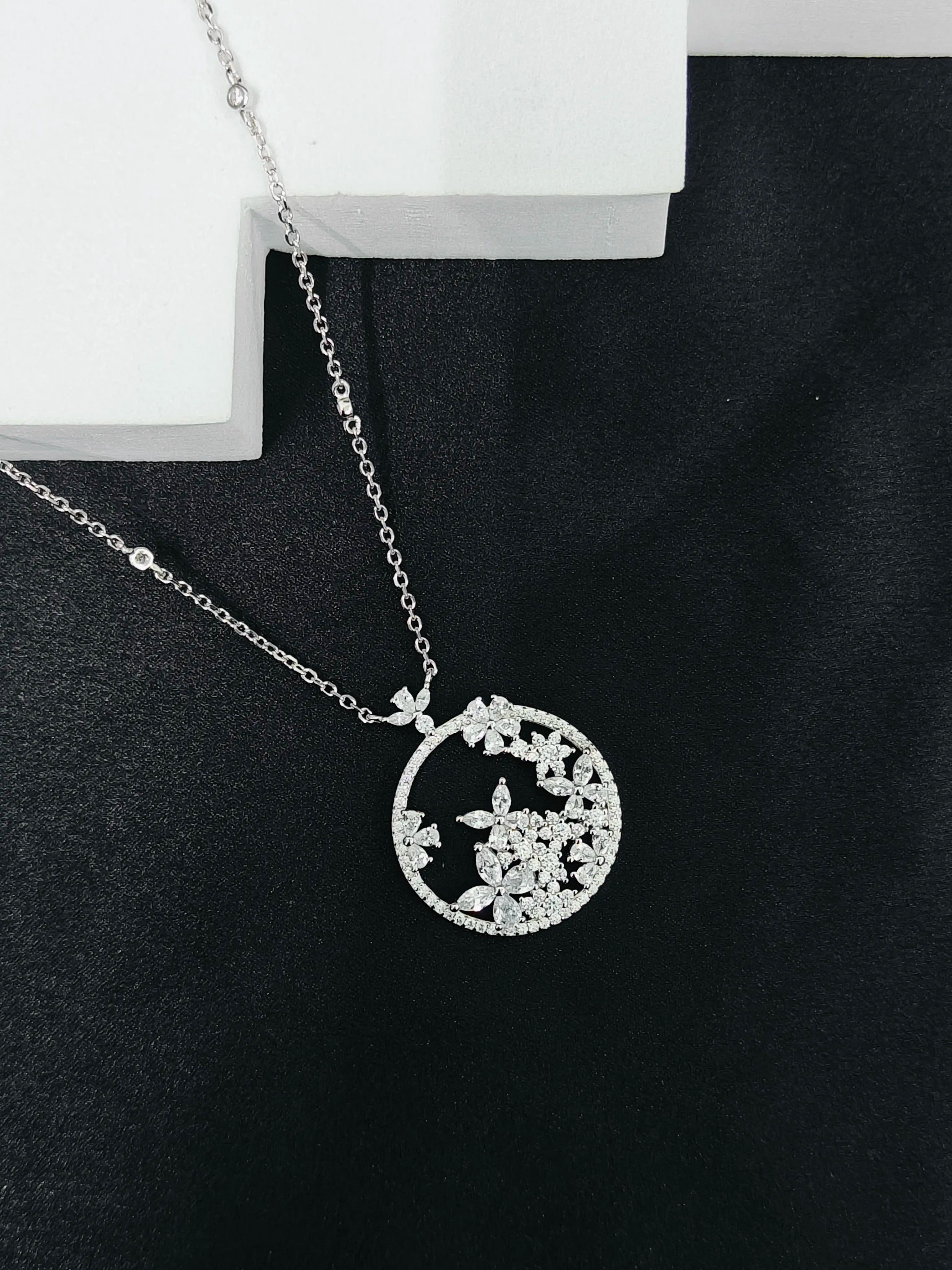 Silver necklace with a round pendant on a black surface