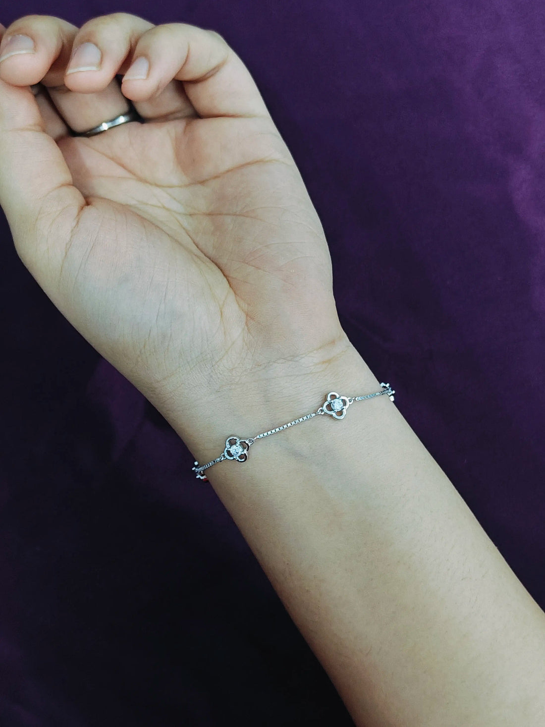 Silver bracelet on a wrist against a purple background