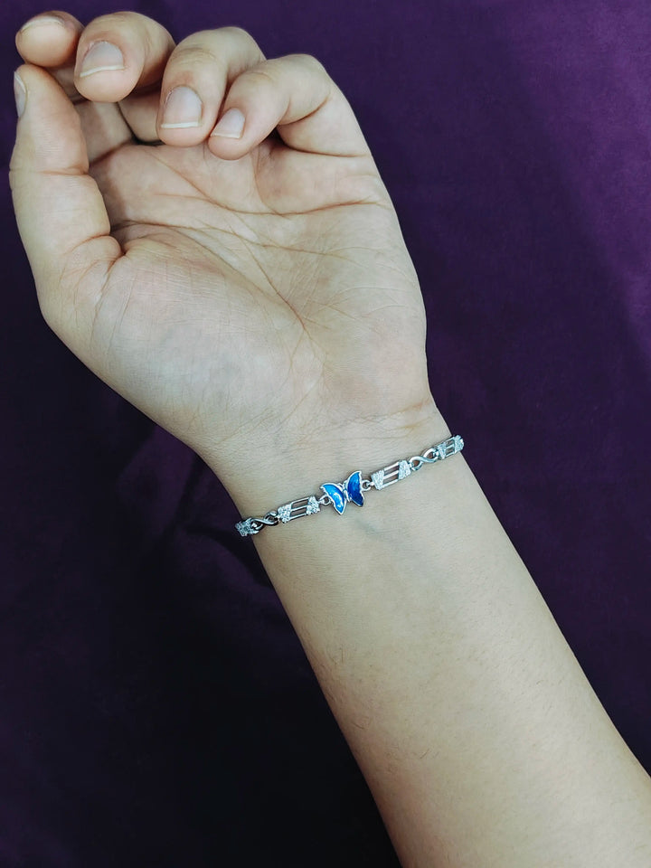 Hand wearing a silver bracelet with a blue stone against a dark background