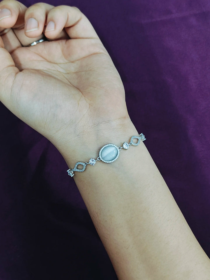 Silver bracelet on a wrist against a purple background