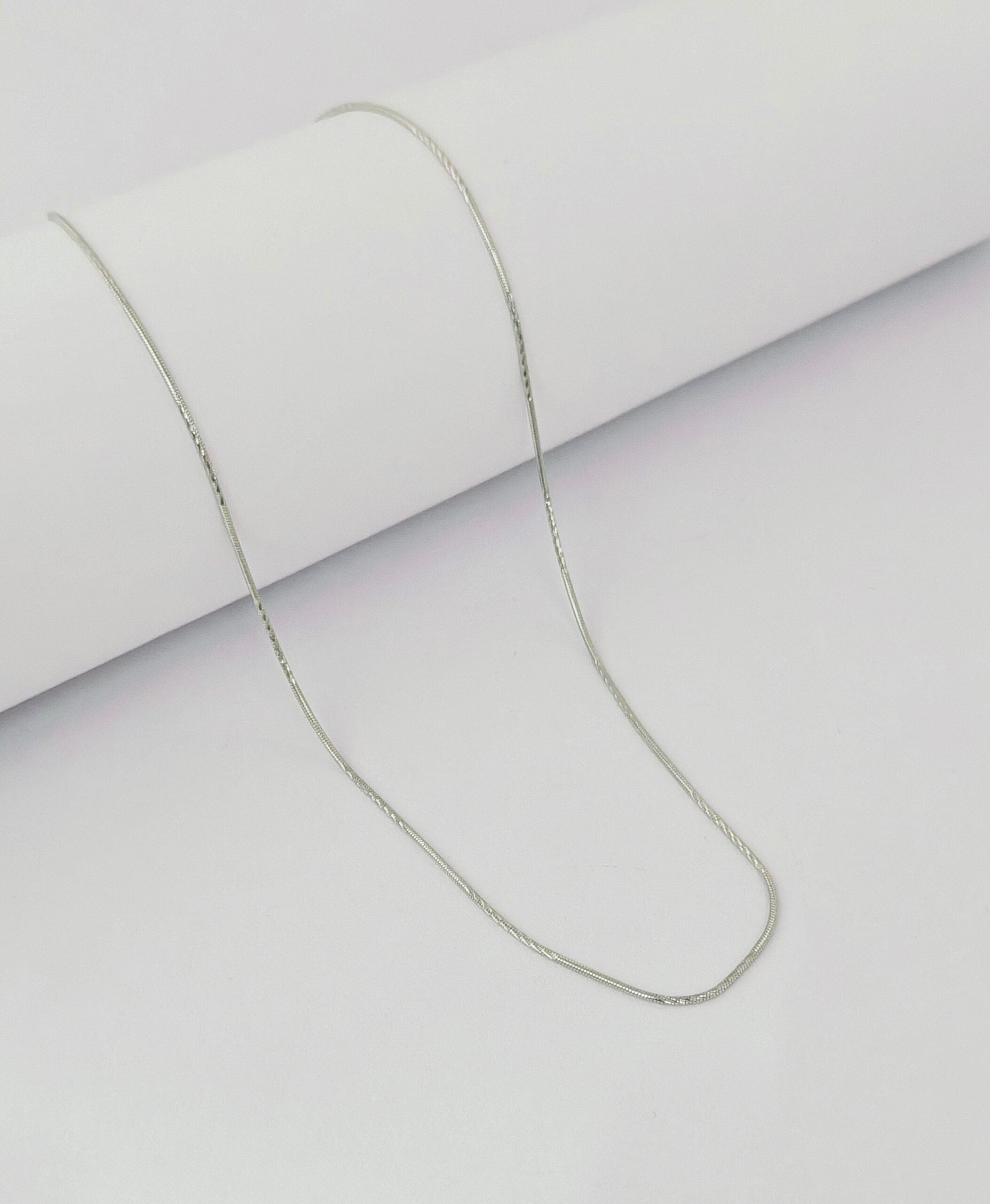 Silver chain necklace on a light gray background