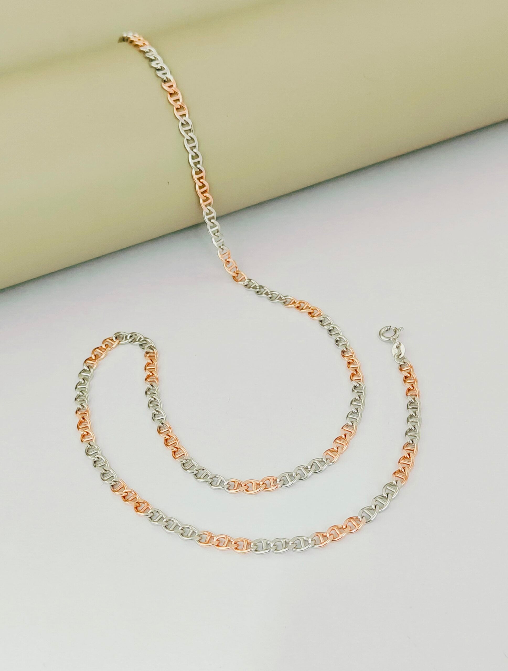 Two gold necklaces on a light gray surface