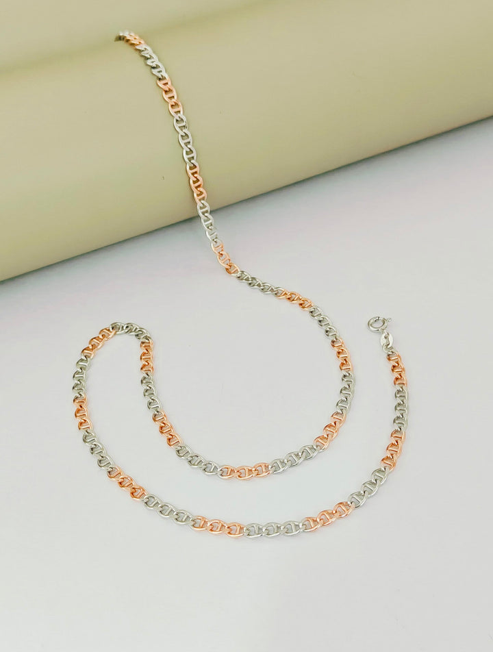 Two gold necklaces on a light gray surface