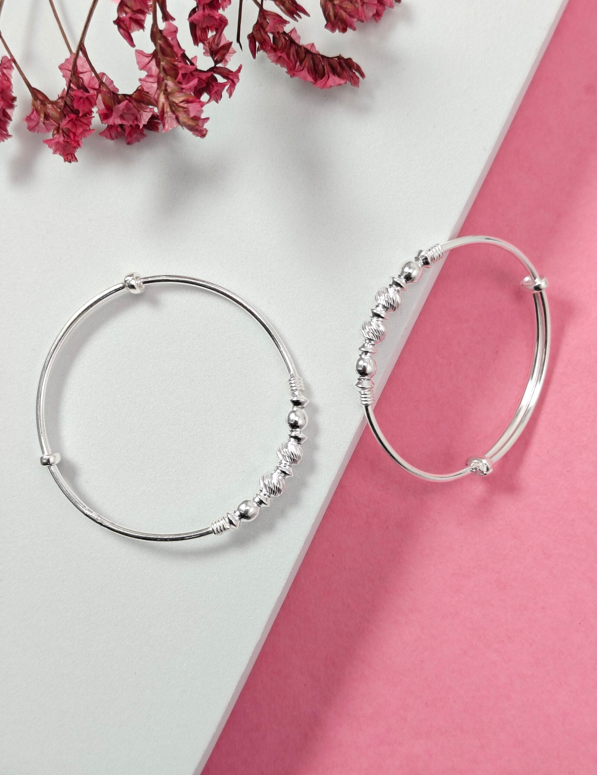Silver hoop earrings with bead detailing on a pink and white background