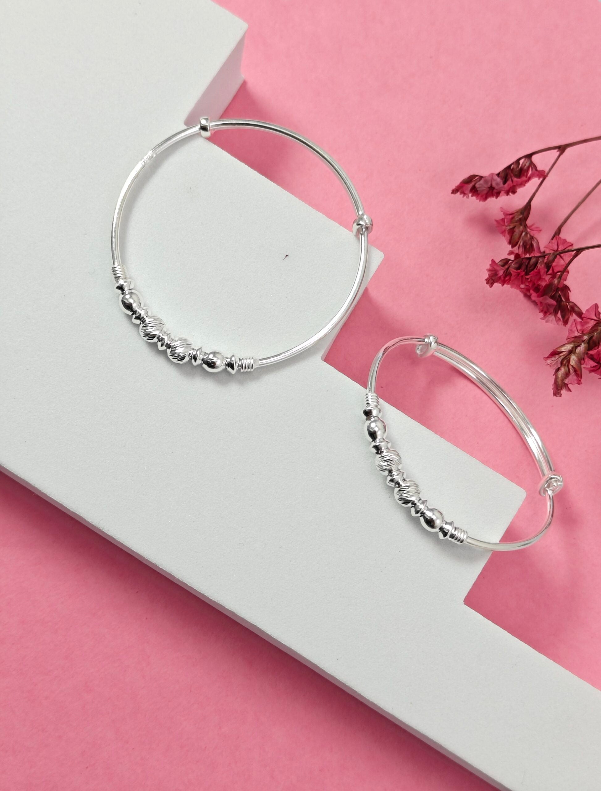 Silver hoop earrings on a white stand with a pink background