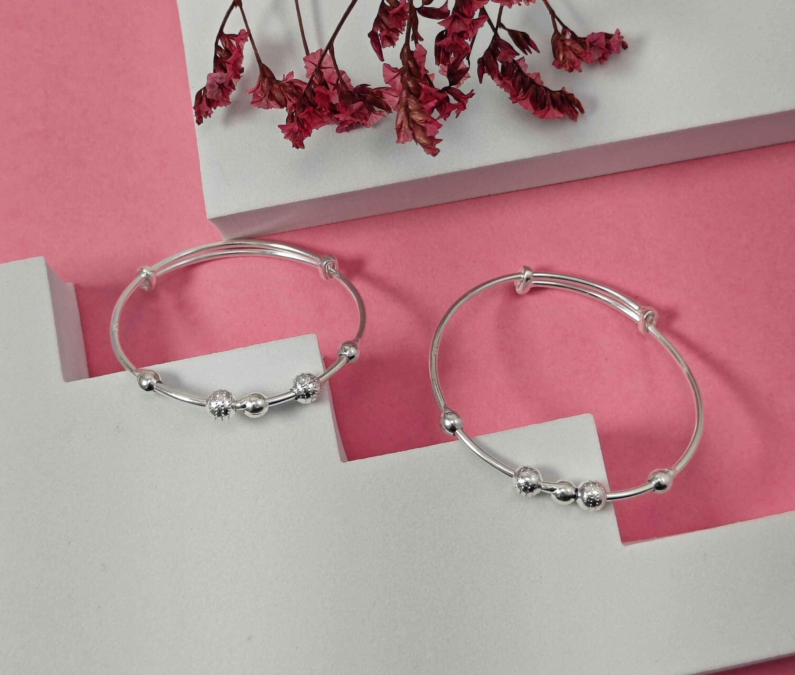 Silver hoop earrings with bead detailing on a pink and white background