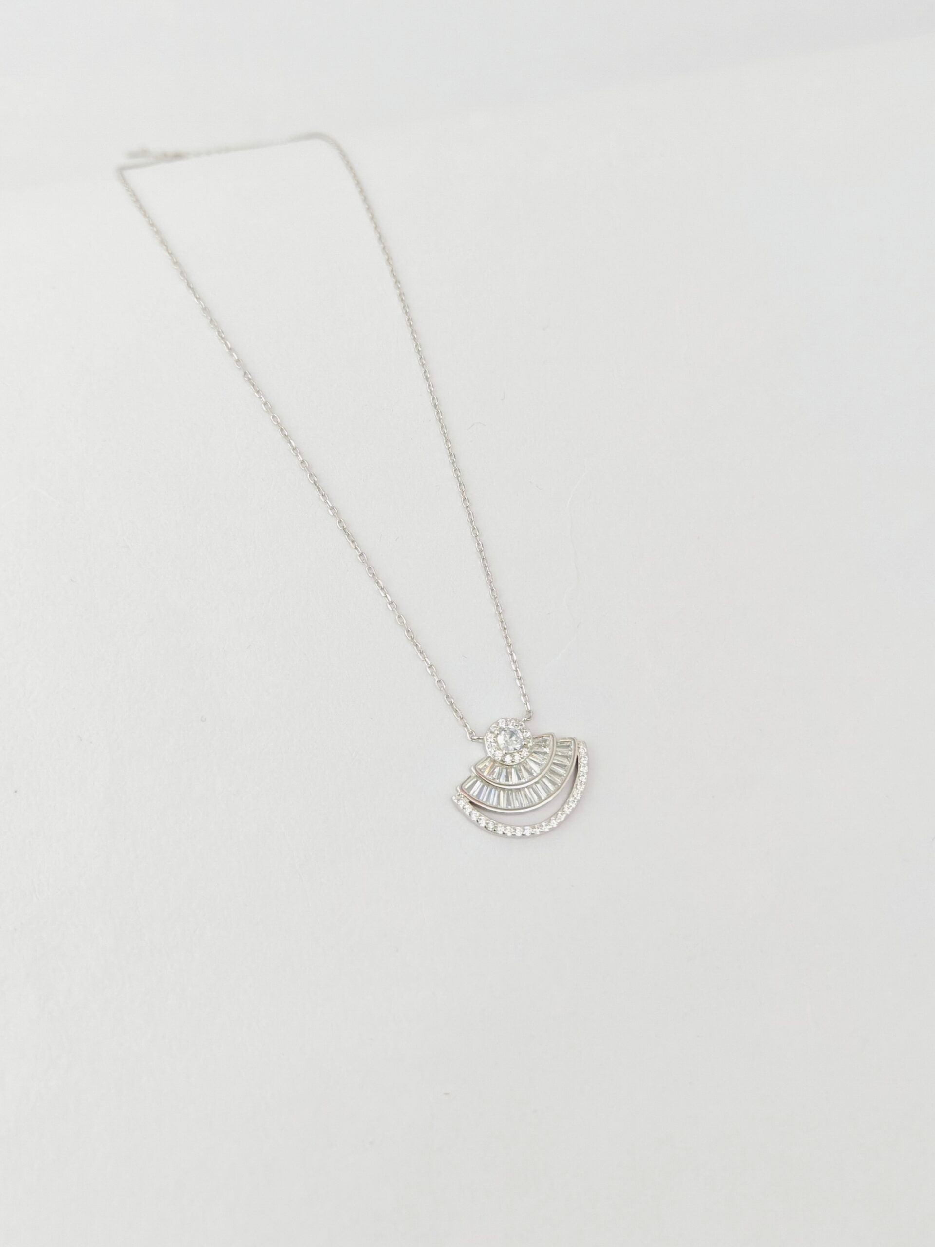 Silver necklace with a half-circle pendant on a light gray background