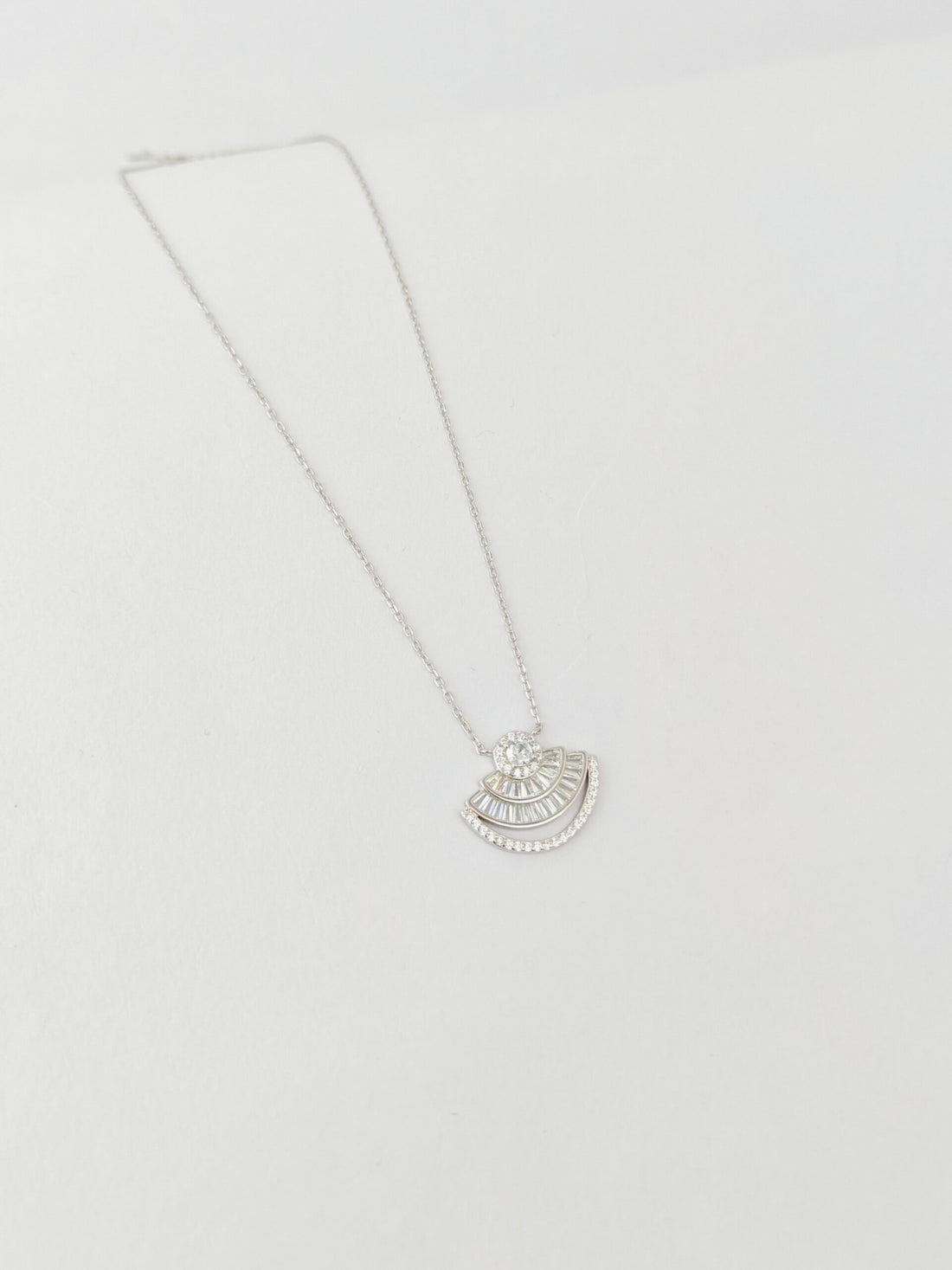 Silver necklace with a half-circle pendant on a light gray background