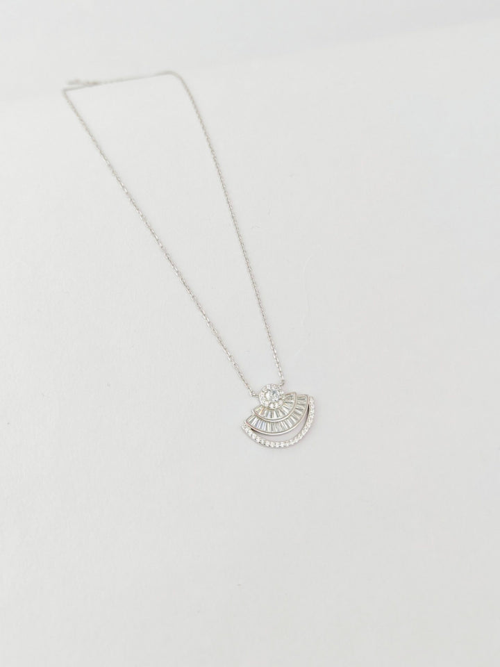 Silver necklace with a half-circle pendant on a light gray background