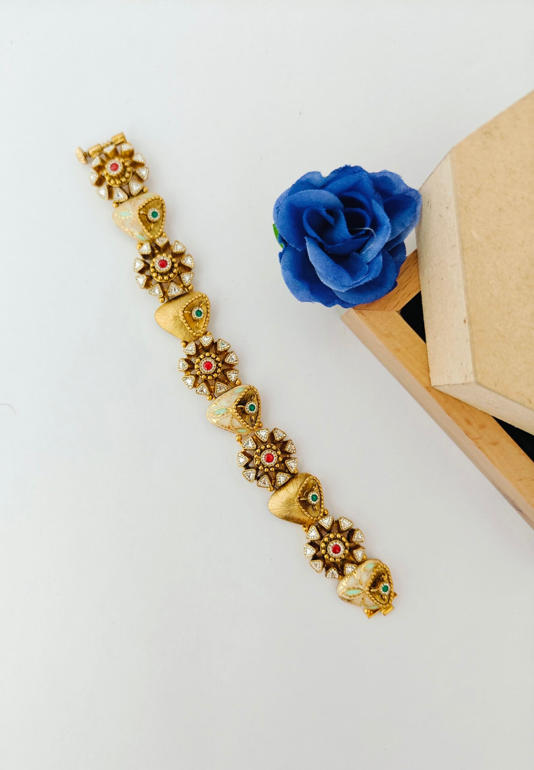 Decorative gold bracelet with floral design on a white surface