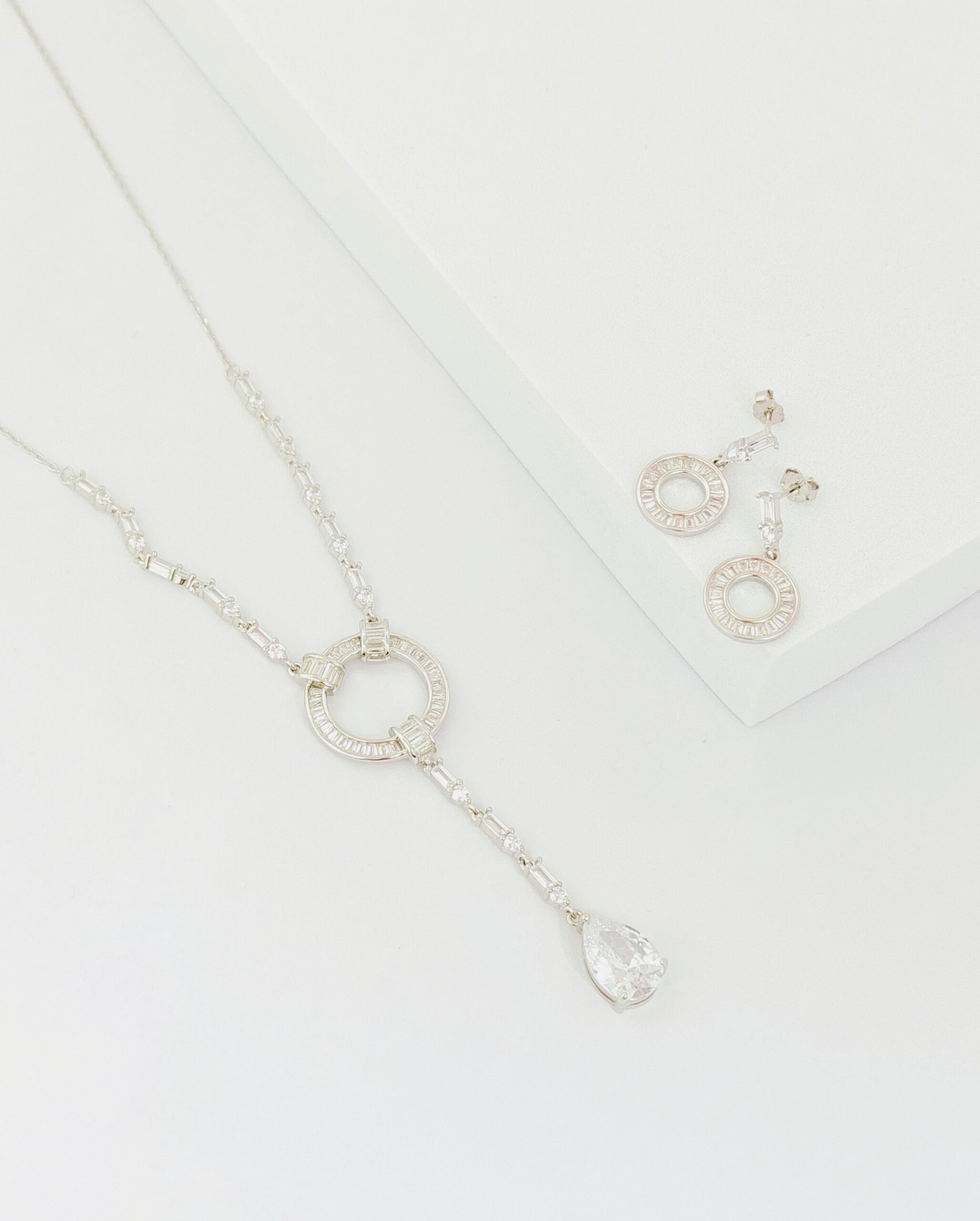 Silver necklace and earrings on a white background