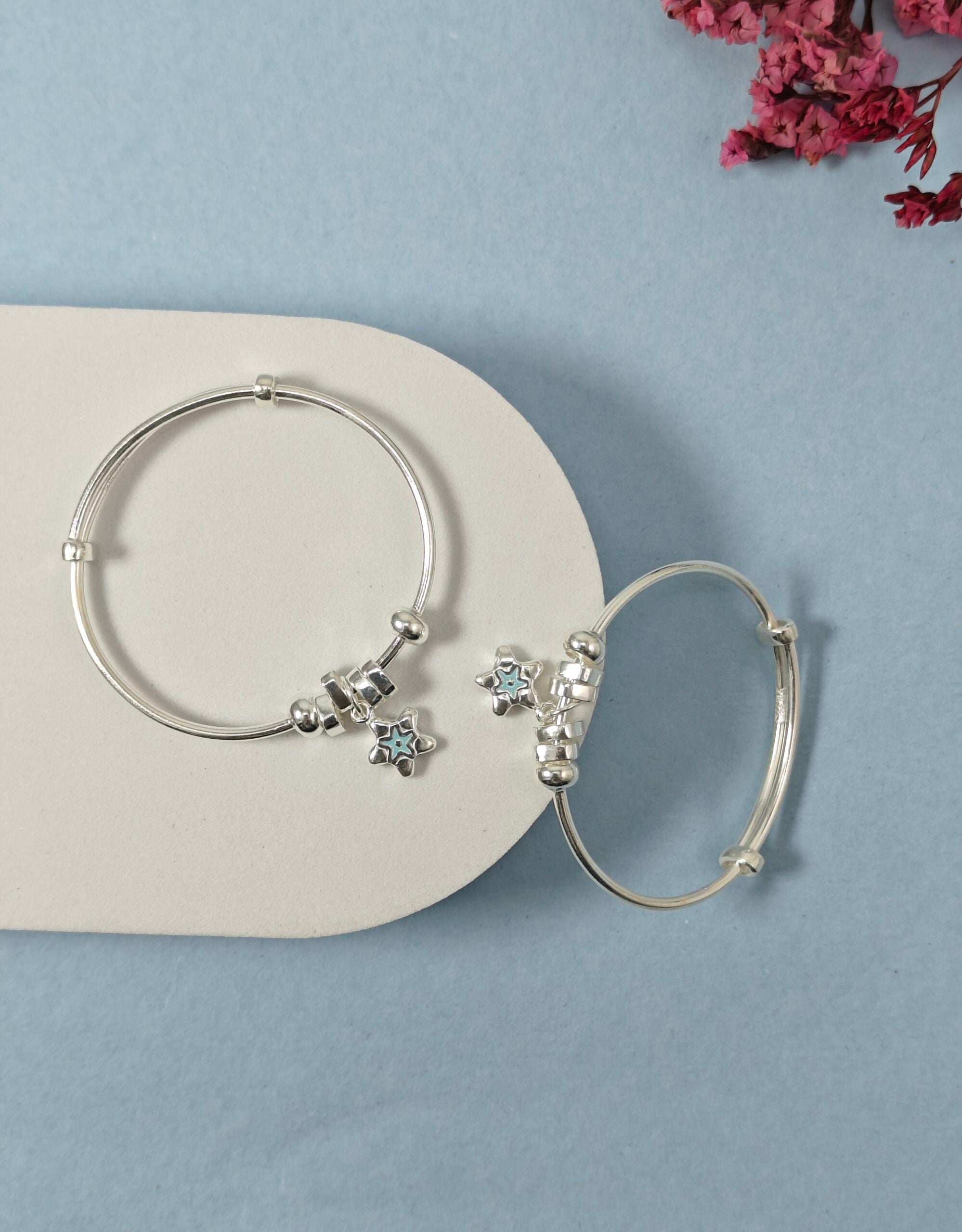 Silver hoop earrings with star-shaped charms on a light blue background