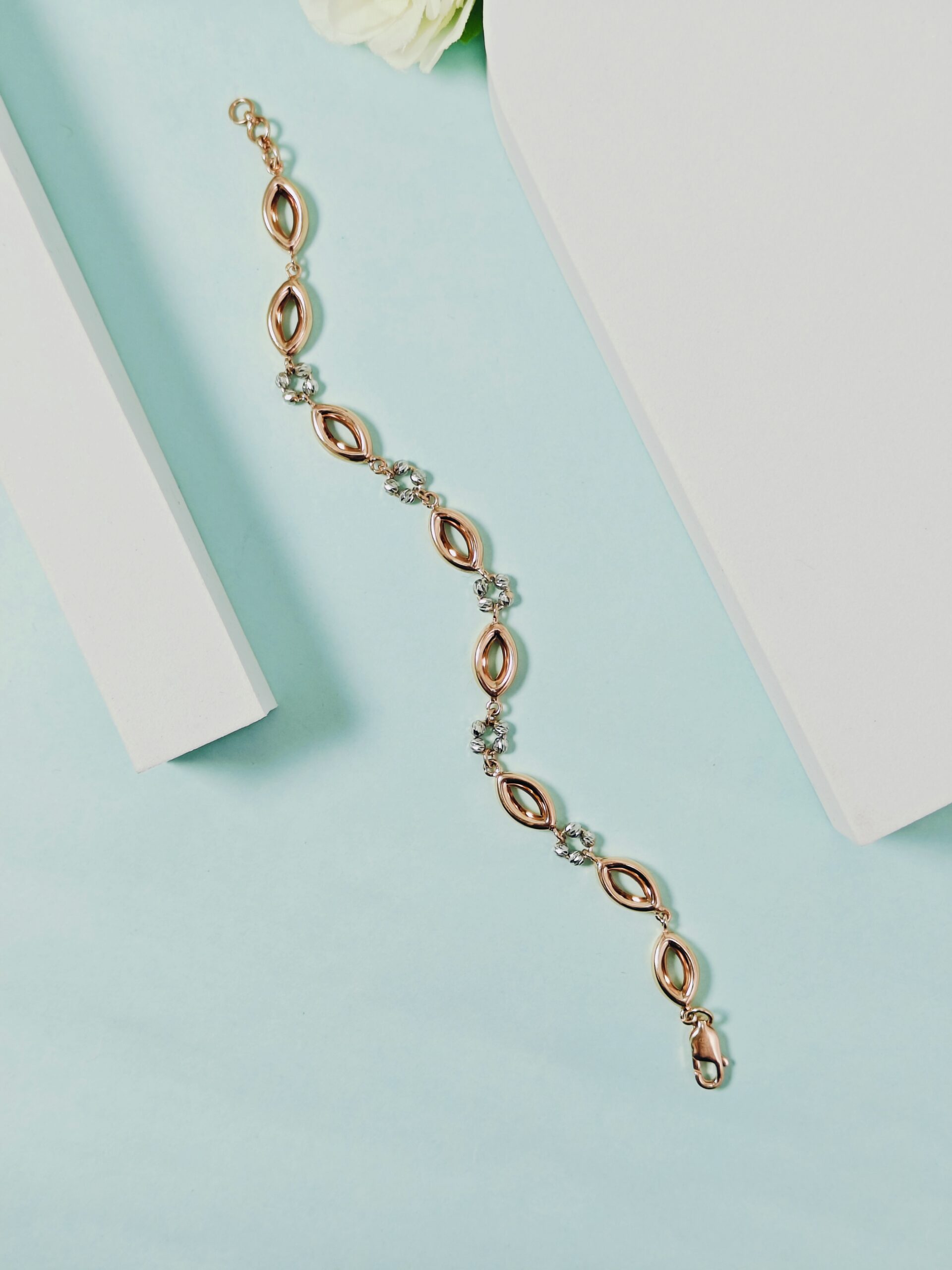 Rose gold bracelet with clear stones on a light blue background