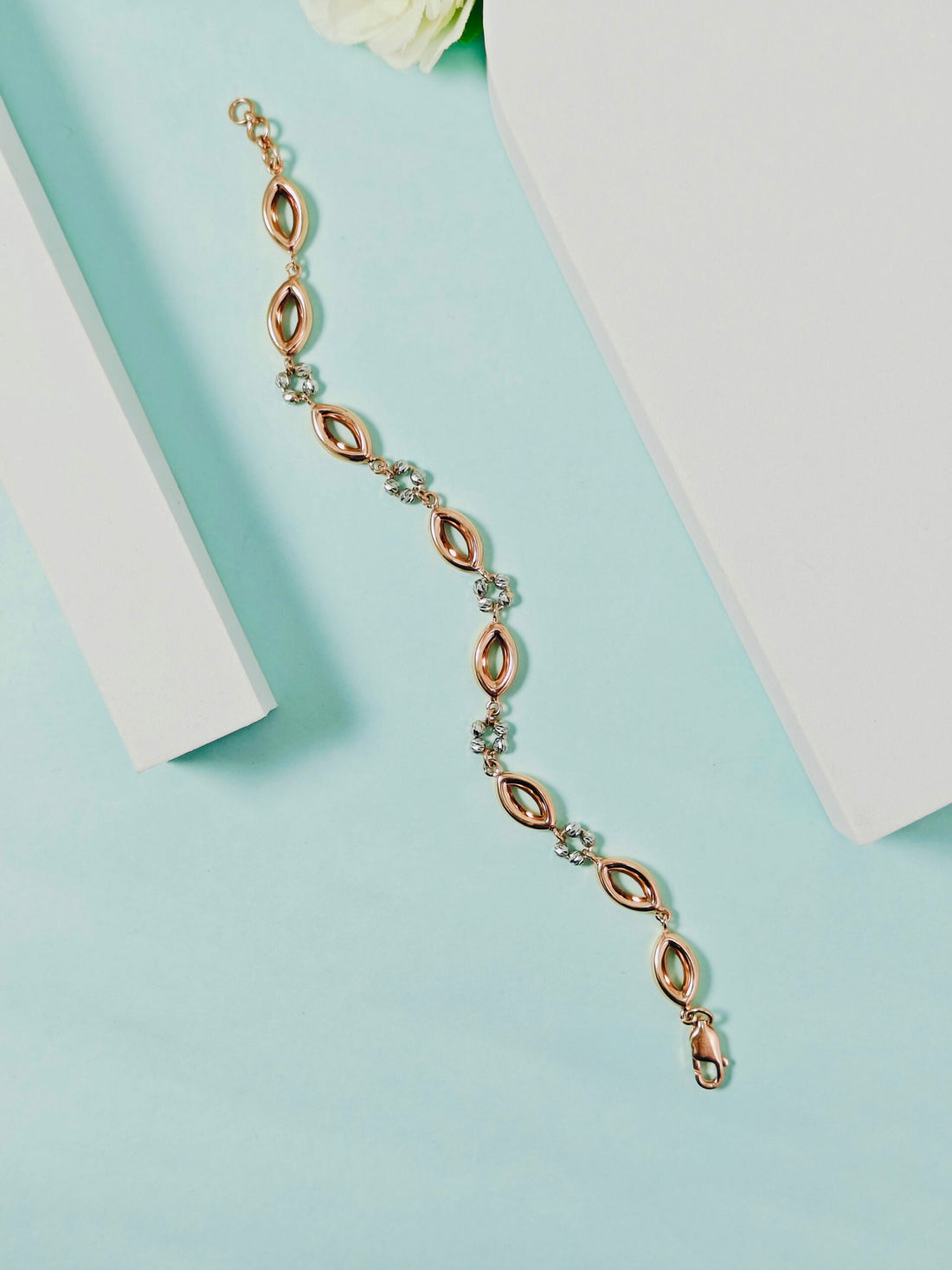 Rose gold bracelet with clear stones on a light blue background