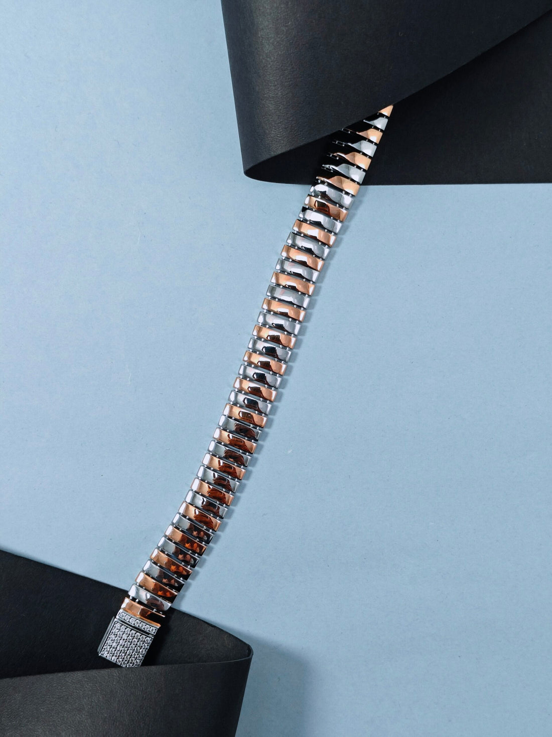 Metallic watch strap on a light blue background