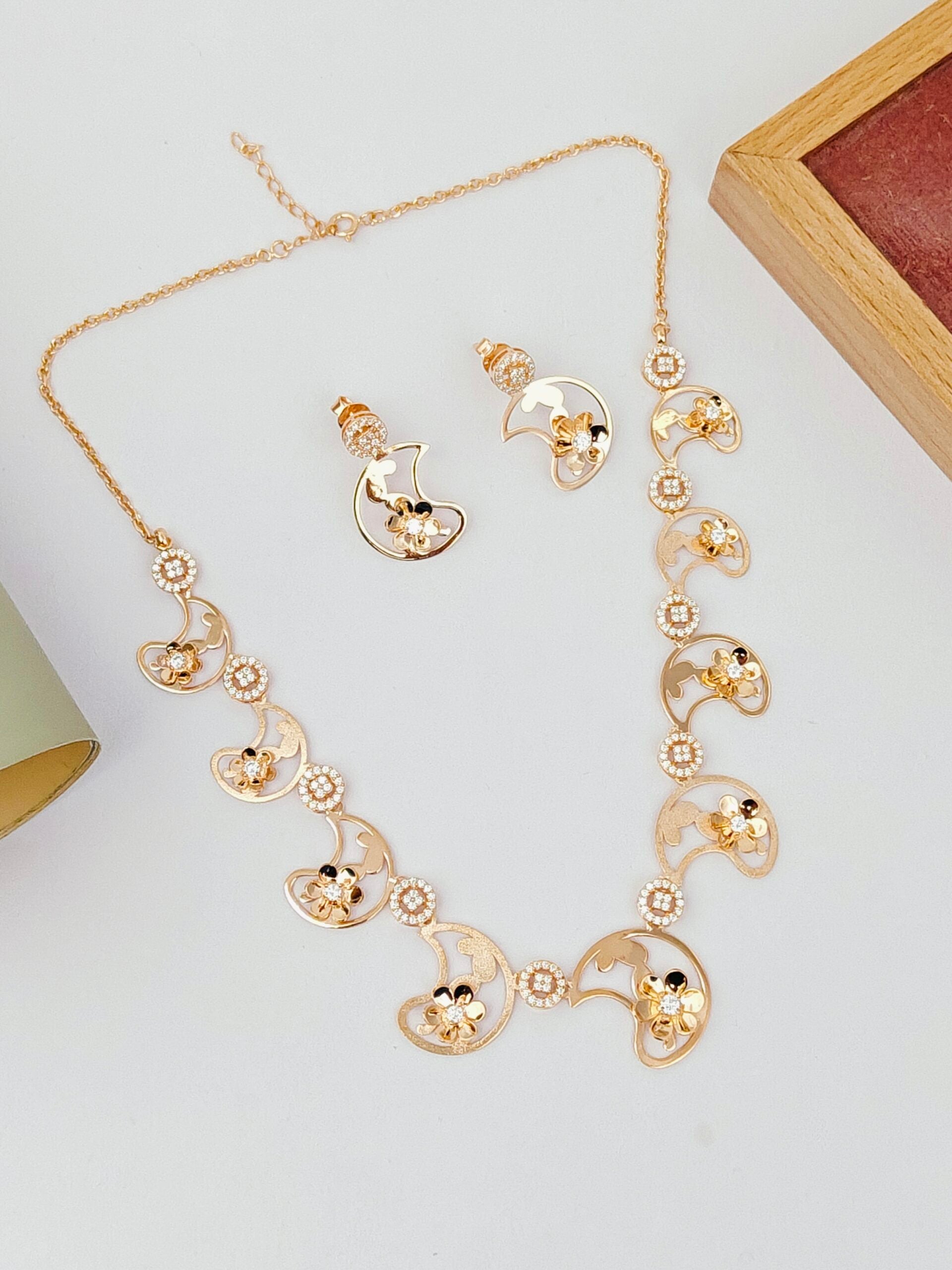 Gold necklace and earrings on a light gray background