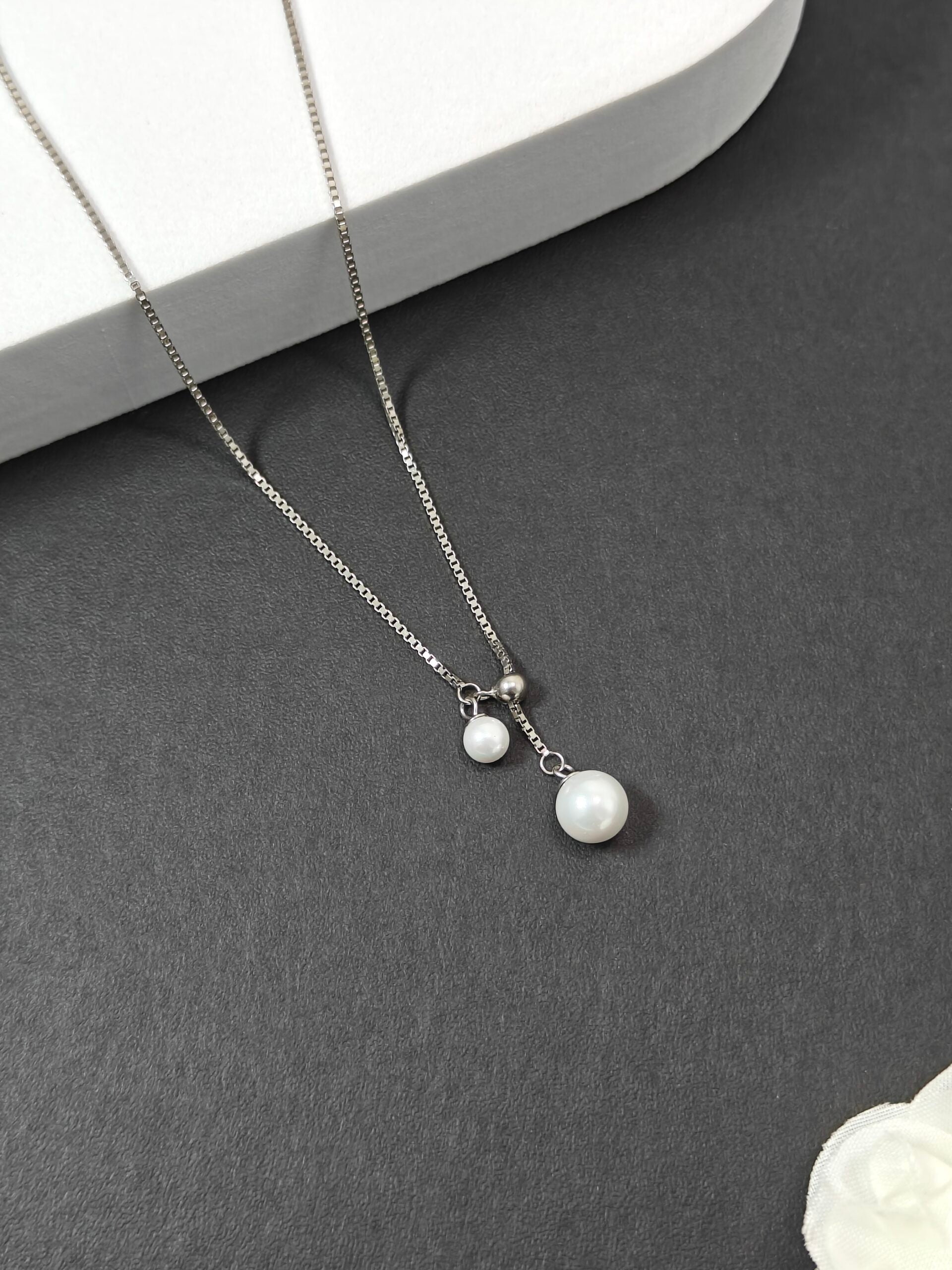 Silver necklace with pearl pendants on a dark surface