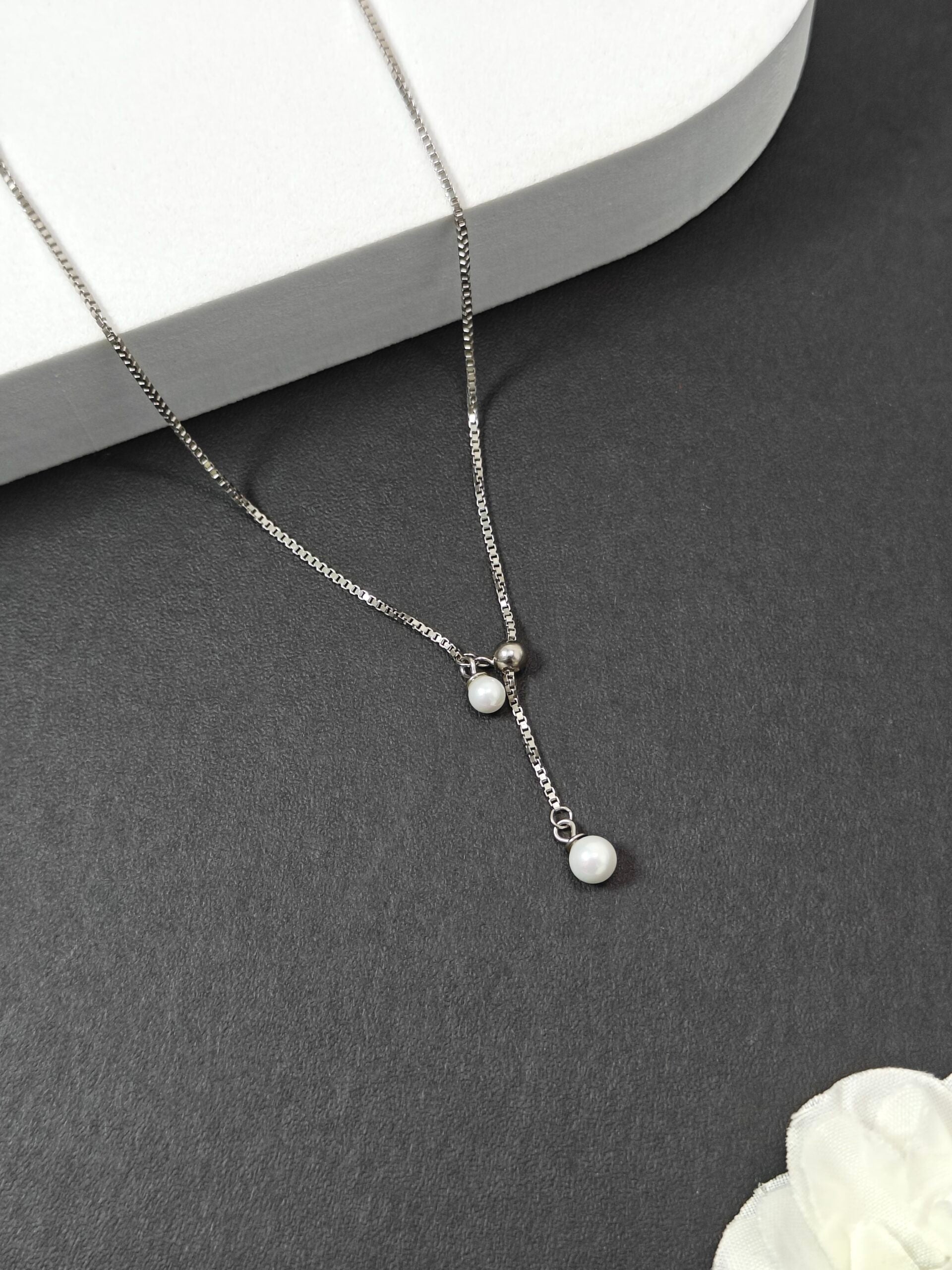 Silver necklace with pearls on a dark surface