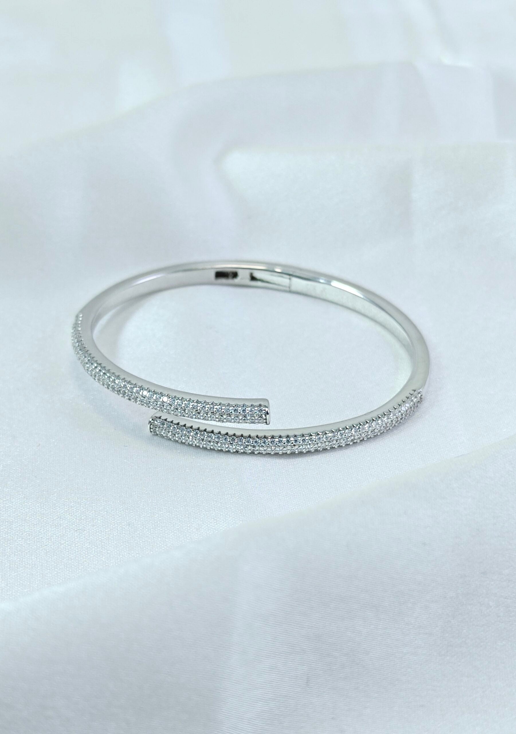 Silver bangle with embedded stones on a white background