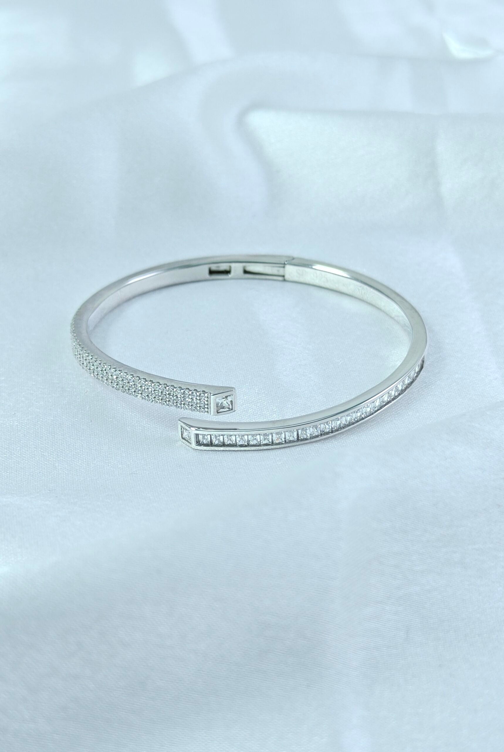 Silver bracelet with small stones on a light gray background