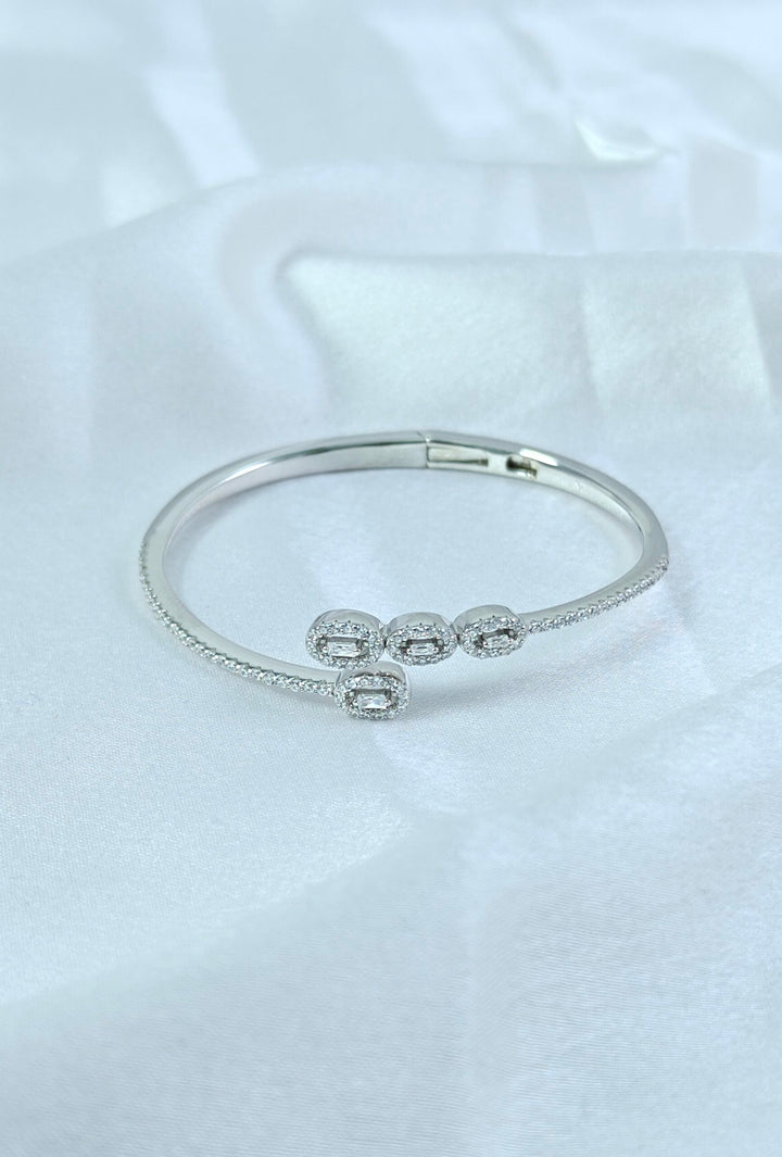 Silver bracelet with three round embellishments on a white fabric background