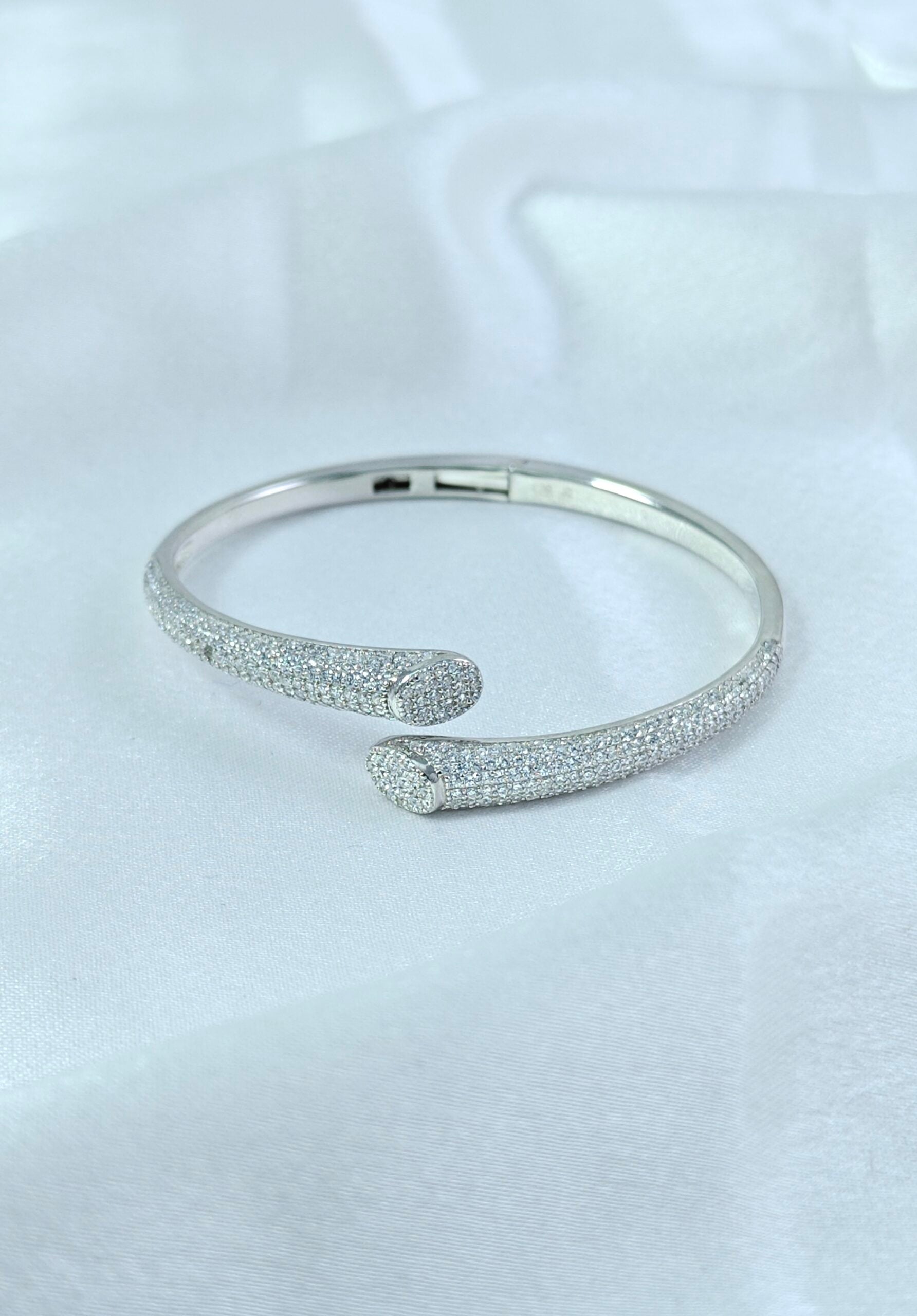 Silver bangle with textured design on a light gray background