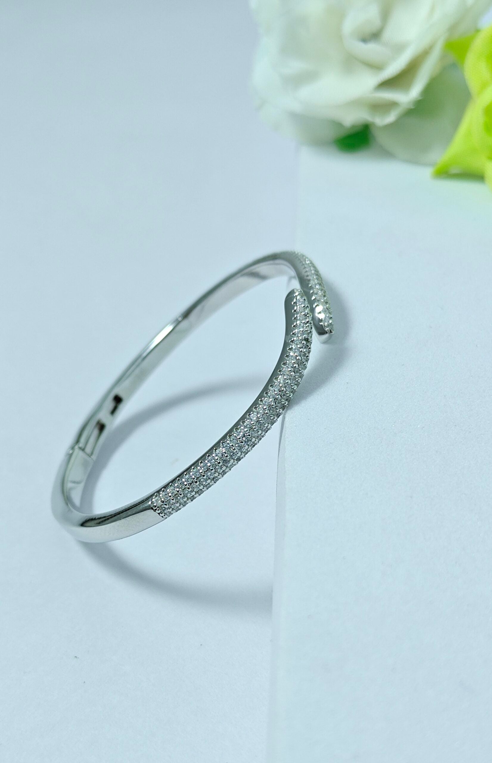 Silver bracelet on a light gray background with white roses.