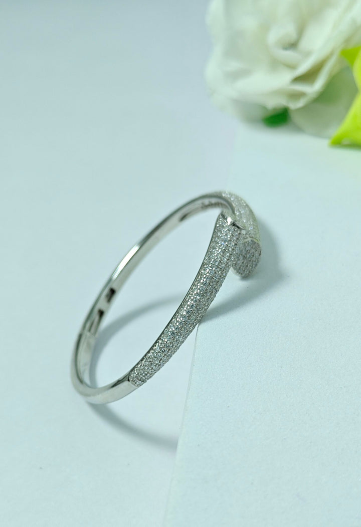 Silver bracelet on a light gray background with a white rose.