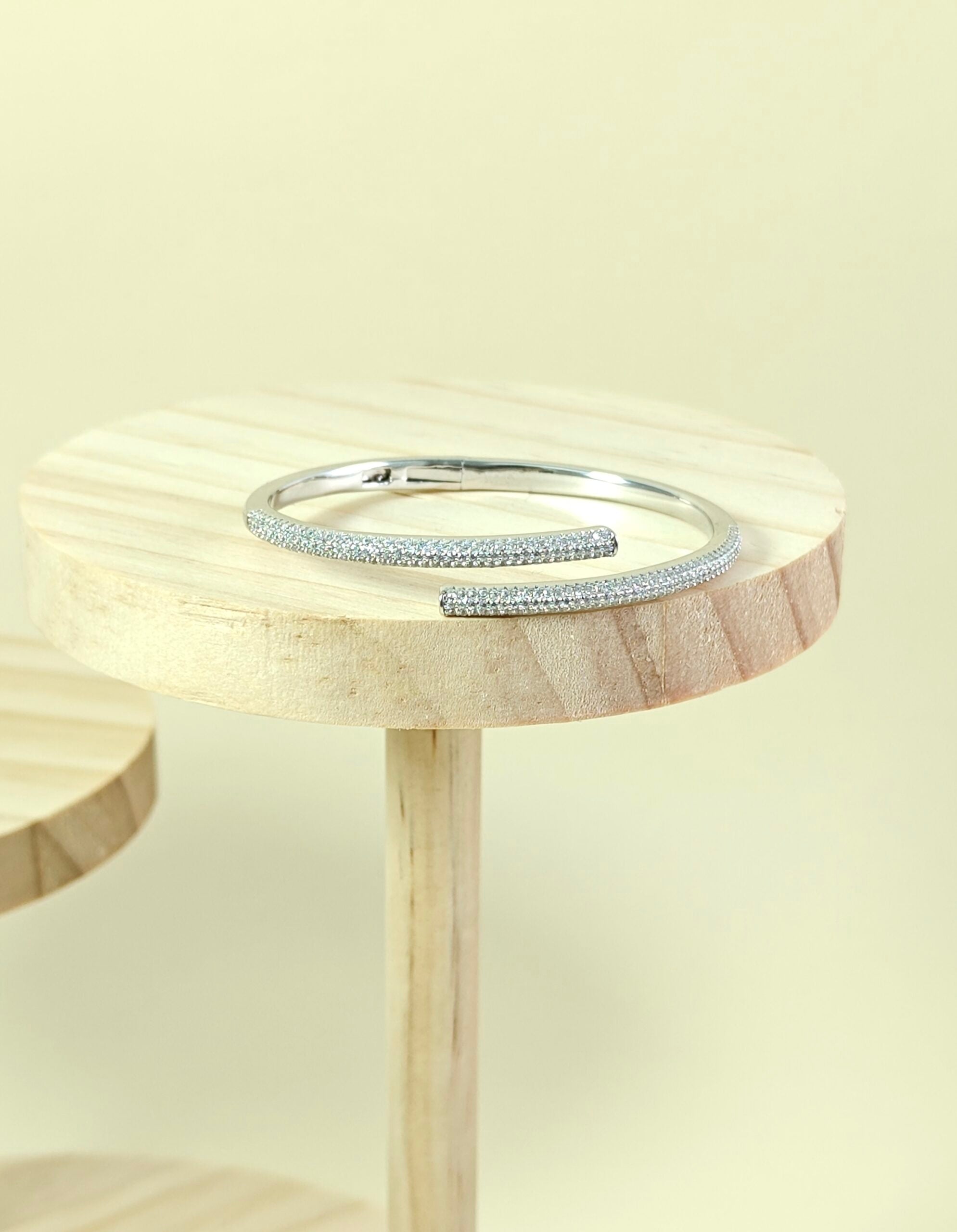 Silver bracelet on a wooden stand with a light background