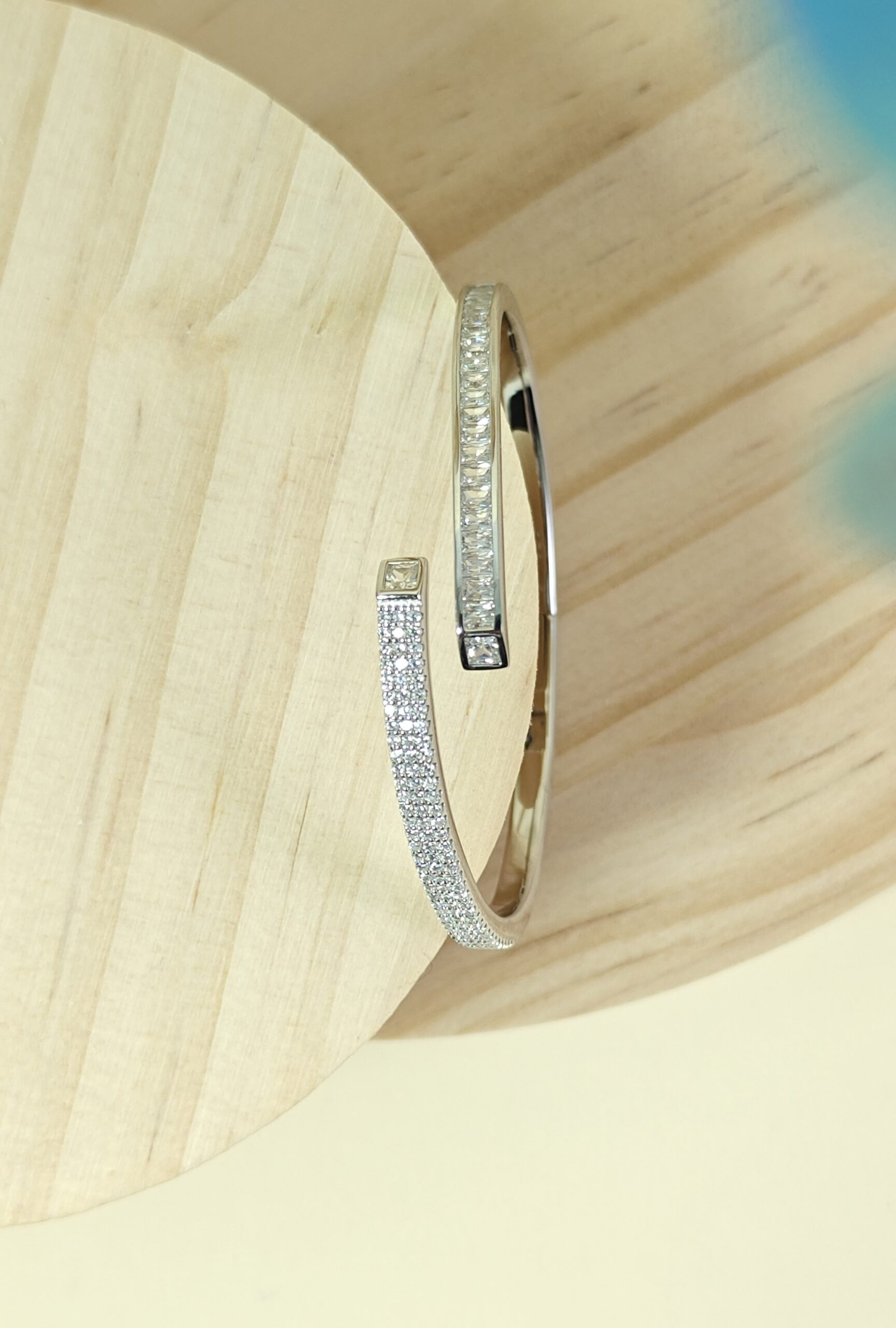 Silver bracelet with small diamonds on a light wood background